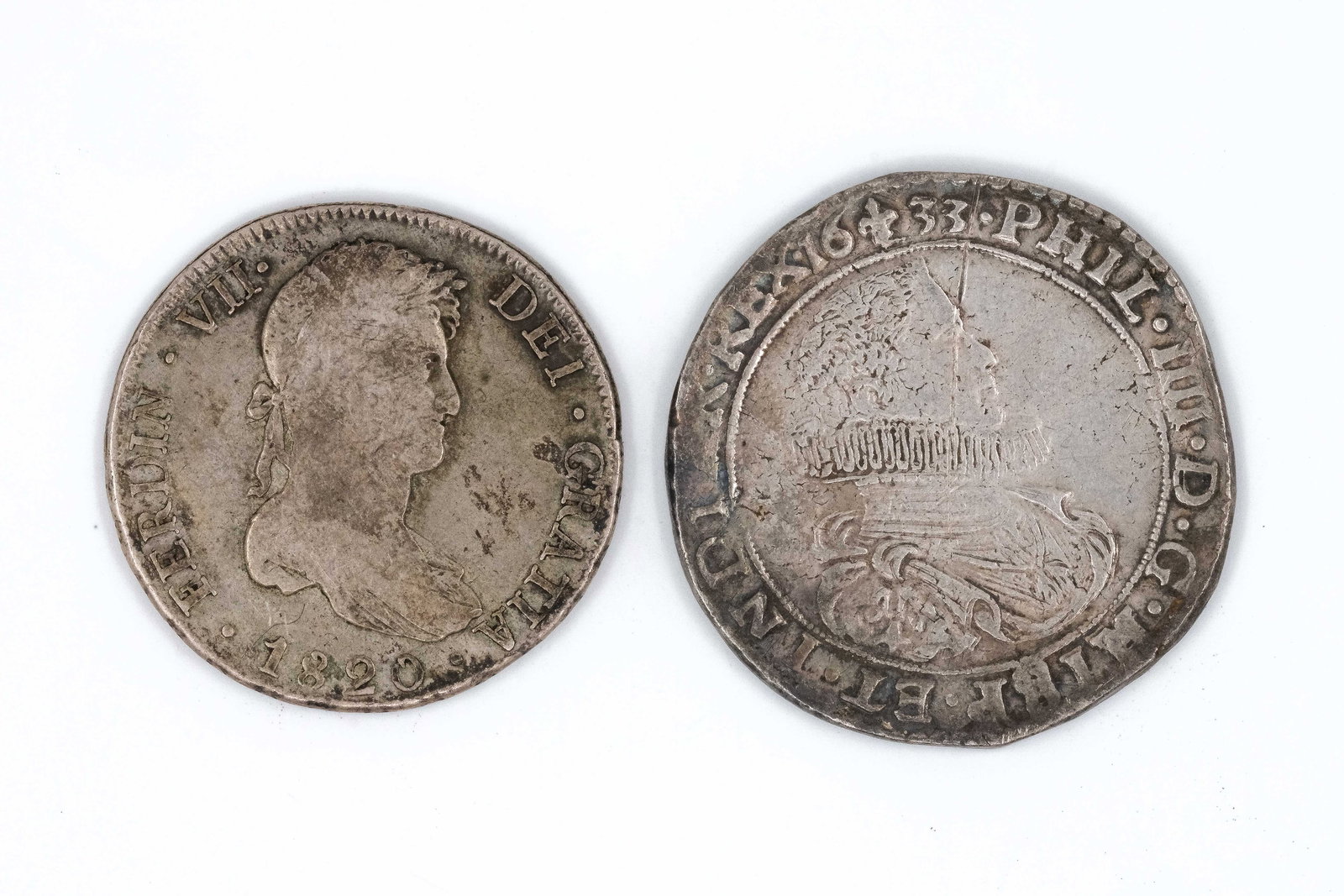 A lot of two European silver coins, dated 1633 and 1820: A lot of two European silver coins, dated 1633 and 1820. Comprising a Spanish 8 Reales of Ferdinand VII and a coin of Philip IV, with crowned shield reverses. Weight: 26,9 - 32,5g