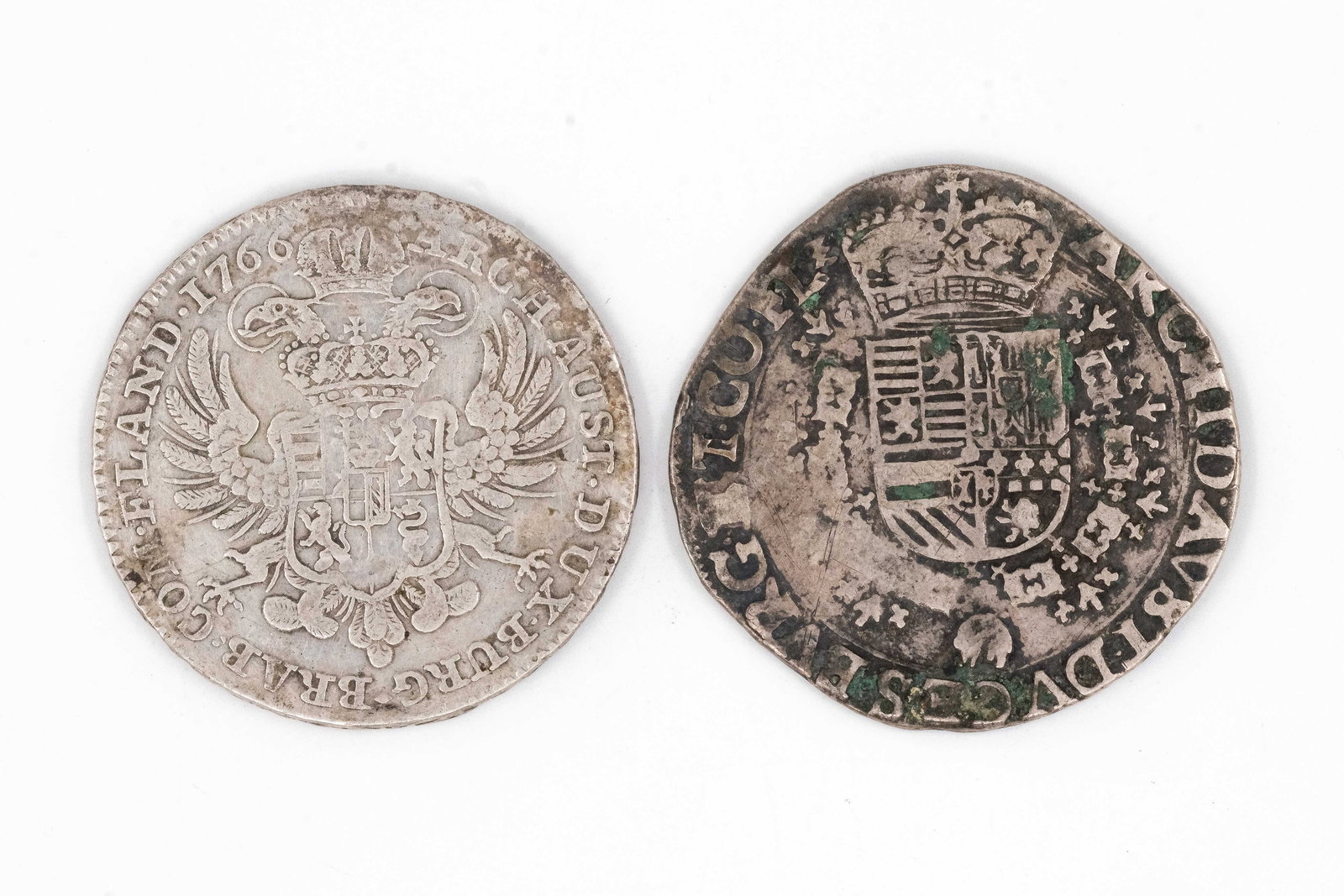 A lot of two European silver coins: A lot of two European silver coins, including an Austrian issue dated 1766 and a Spanish Netherlands issue. With crowned coats of arms and surrounding legends, the reverses with cross motifs and heral