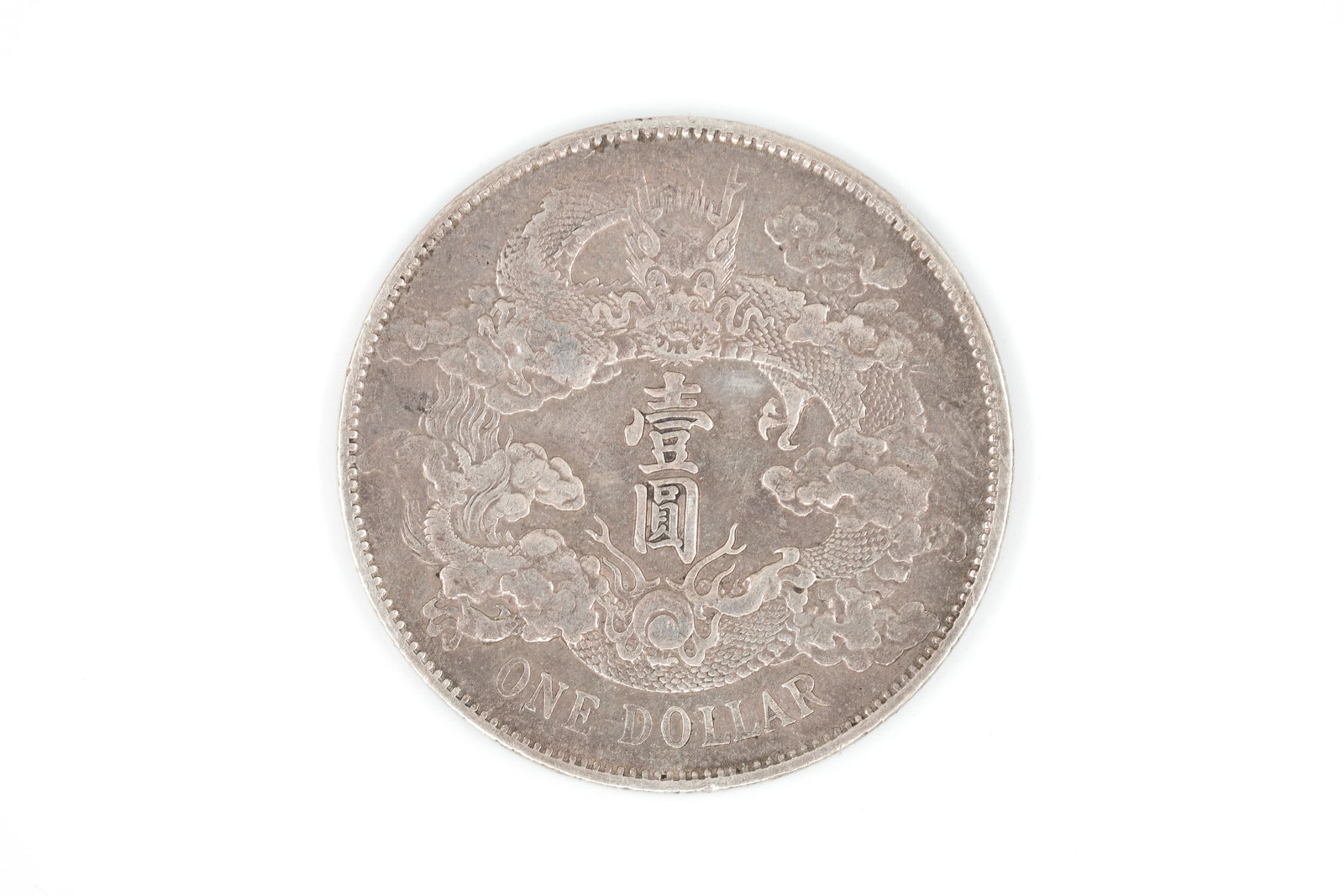 A Chinese silver dollar coin: A Chinese silver dollar coin. Obverse with Chinese characters within wreath, reverse with dragon motif surrounding central inscription and denomination ONE DOLLAR below. Weight: 26,9g