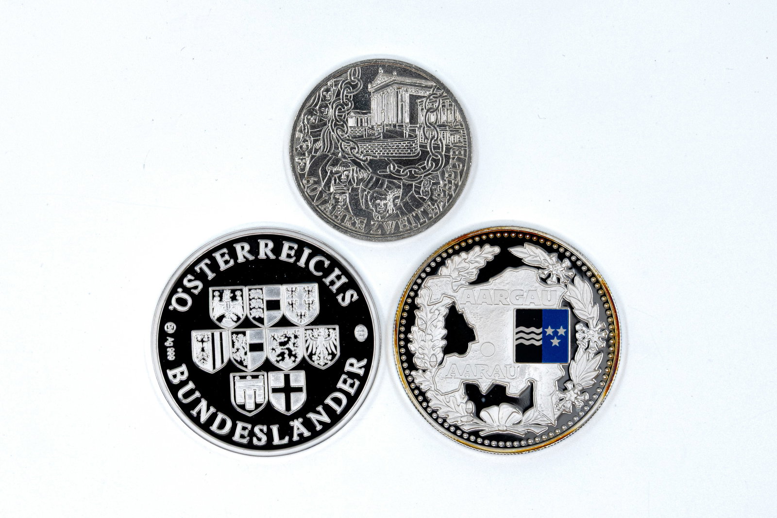 A lot of three various modern silver commemorative coins: A lot of three various modern silver commemorative coins. Comprising two Austrian issues and one Swiss commemorative piece, with heraldic, architectural and regional designs. Total weight: 72,7g