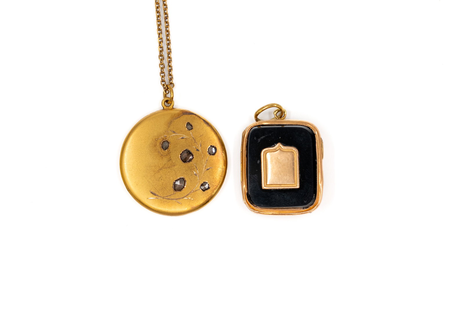 A composed lot of two antique 18k and 14k gold pendants: A composed lot of two antique 18k and 14k gold pendants, one of which decorated with rose-cut diamonds and together with its gold chain.The black 14k gold pendant shows damage, condition report availa
