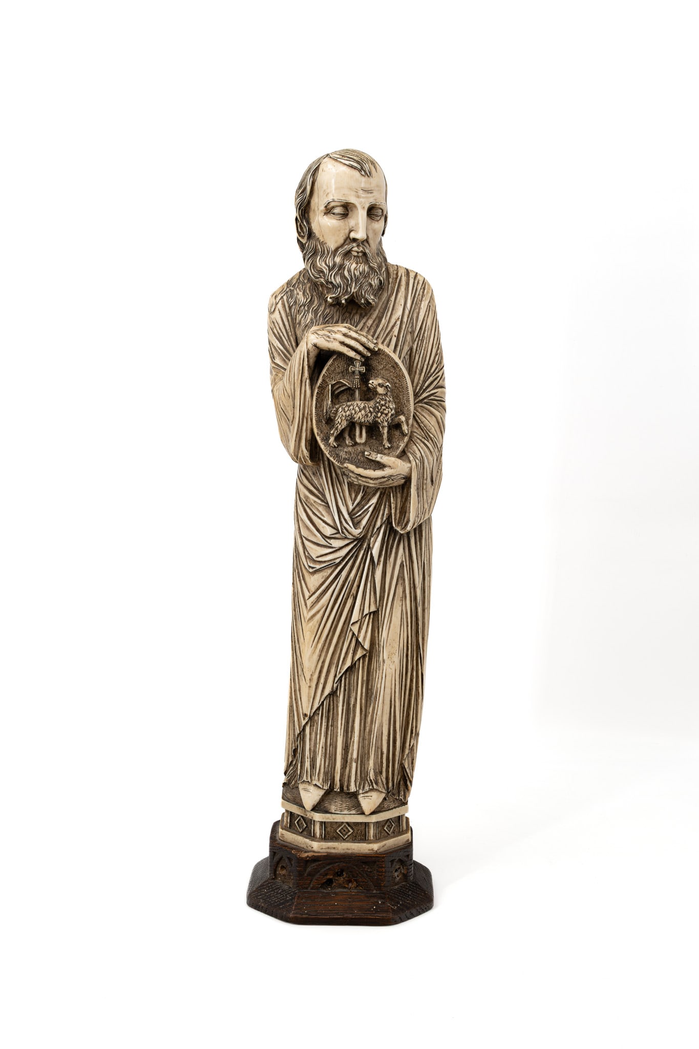 A large and antique carved ivory sculpture representing Saint John the Baptist: A large and antique carved ivory sculpture representing Saint John the Baptist, holding an Agnus Dei medallion. Mounted on a wooden base. 19th century. H: 58,5 cm, total Comes with its European CITES 