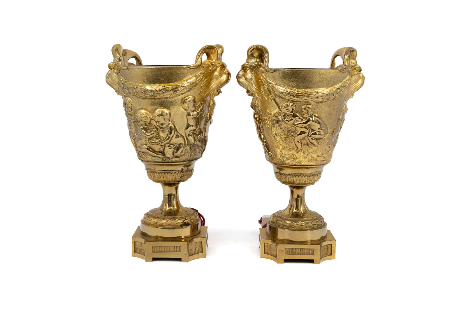 A pair of antique French gilt bronze relief decorated urn lamp vases: A pair of antique French gilt bronze relief decorated urn lamp vases with a Bacchanalian decor. Circa 1900. H: 29 cm