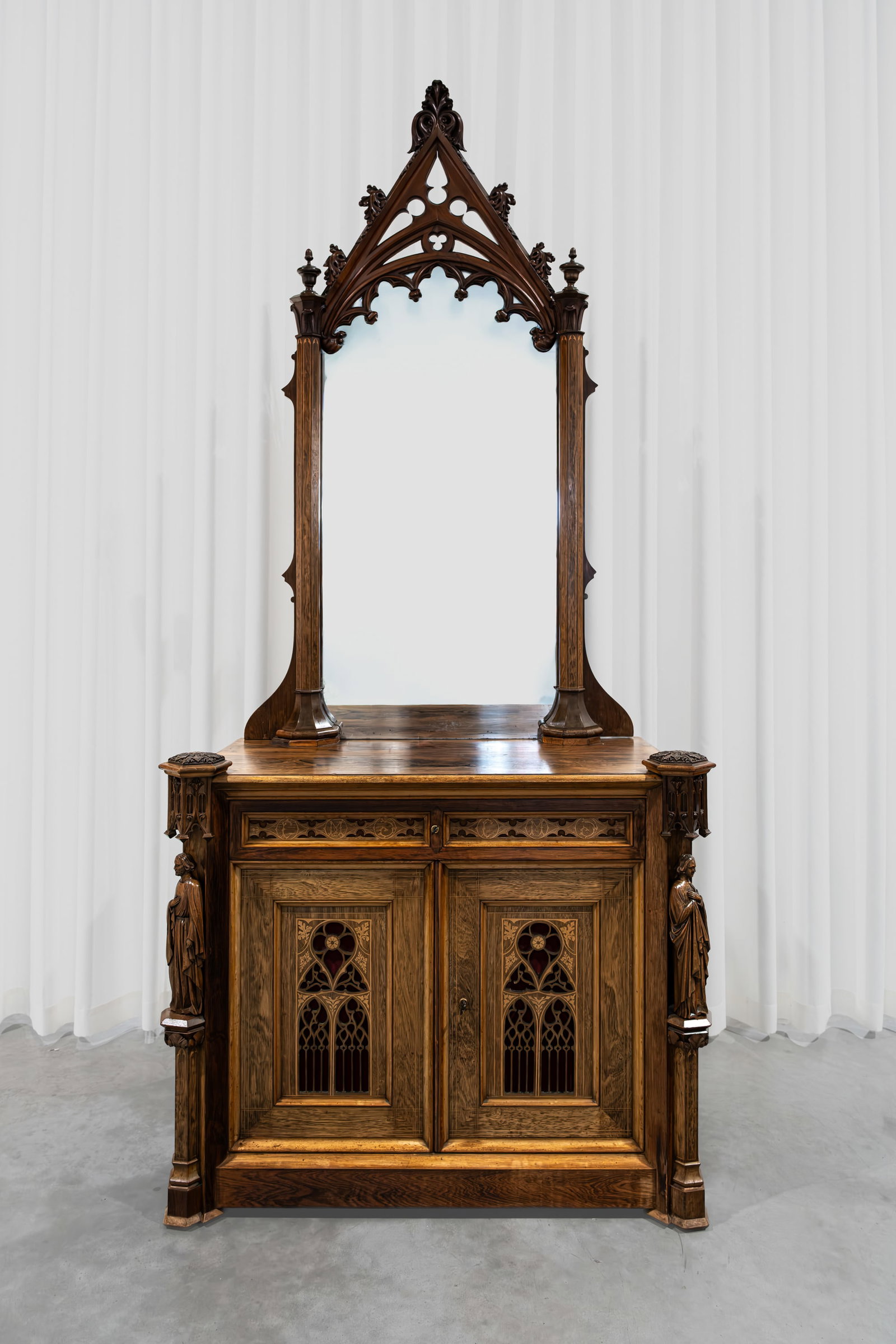 An antique Gothic Revival walnut two doors cabinet with drawers and a mirror: An antique Gothic Revival walnut two-doors cabinet with drawers and a mirror. Finely decorated and carved with figures, leather mounted on the desk part, in two parts demountable. 19th century. H: 260