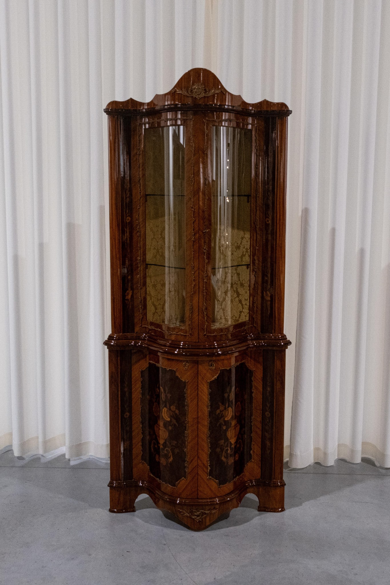 A 20th century corner display cabinet with marquetry veneer wood inlay: A 20th century corner display cabinet with marquetry veneer wood inlay and brass mountings. Circa 1970s. H: 205 - W: 85 - D: 62 cm