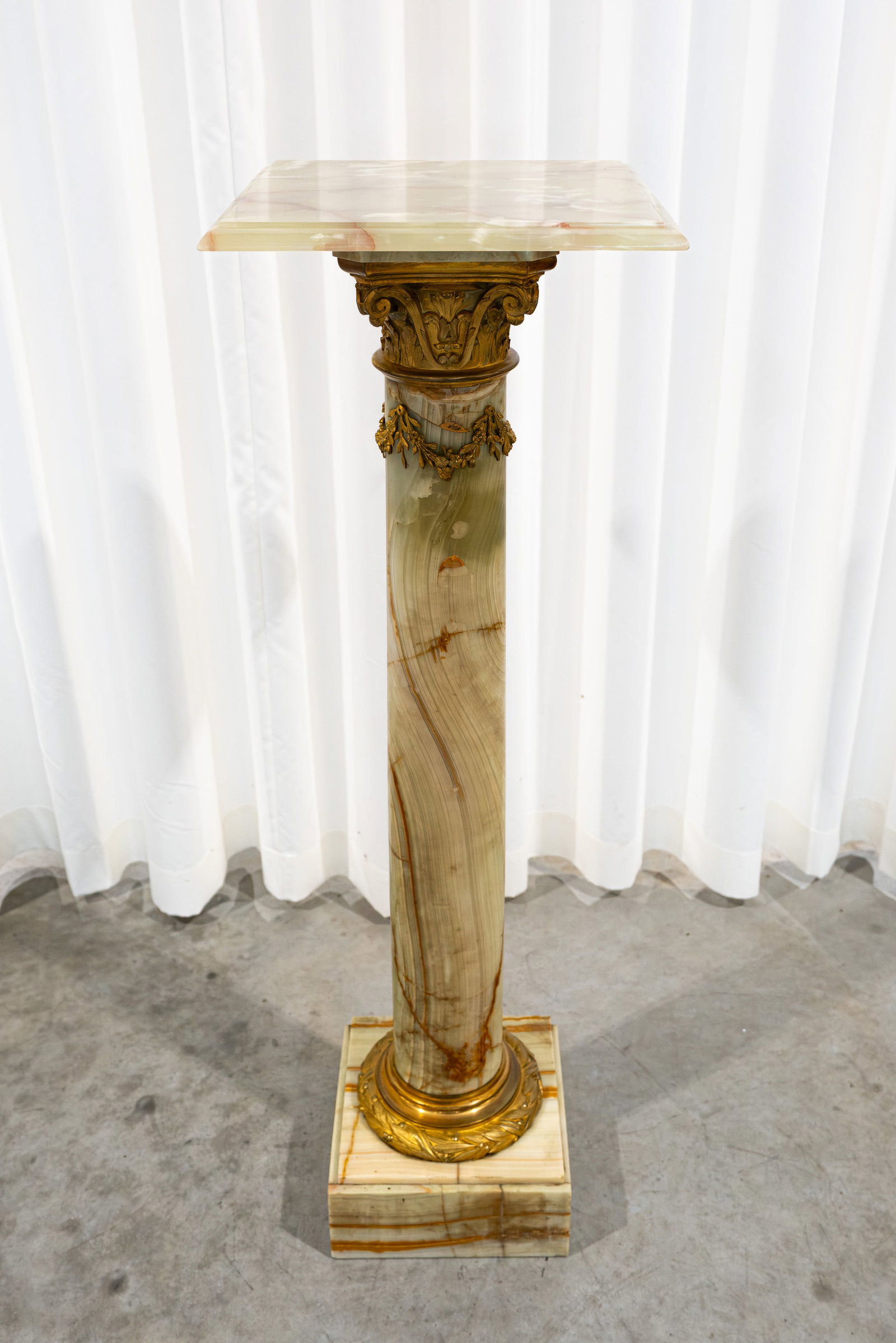 An antique French onyx marble pedestal with gilt bronze mounting: An antique French onyx marble pedestal with gilt bronze mountings. Late 19th century. Condition: backside of the base has one plaque missing, report available on request. H: 110 cm
