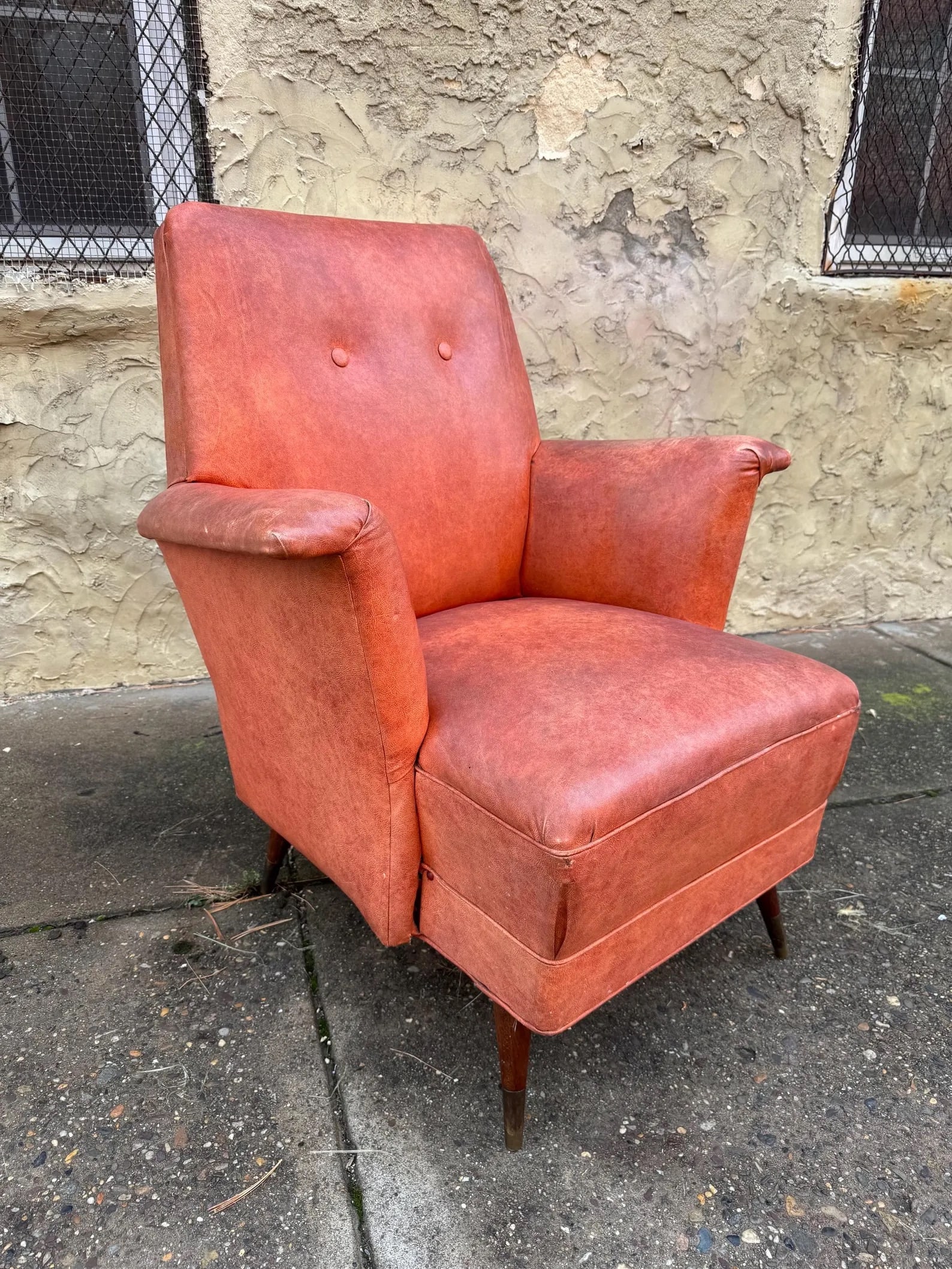 Danish Modern Orange Vinyl Lounge Chair: Clean mid-century modern lounge chair featuring bright orange vinyl upholstery and tapered wooden legs. Minimalist Scandinavian-inspired design with bold color presence and compact proportions.