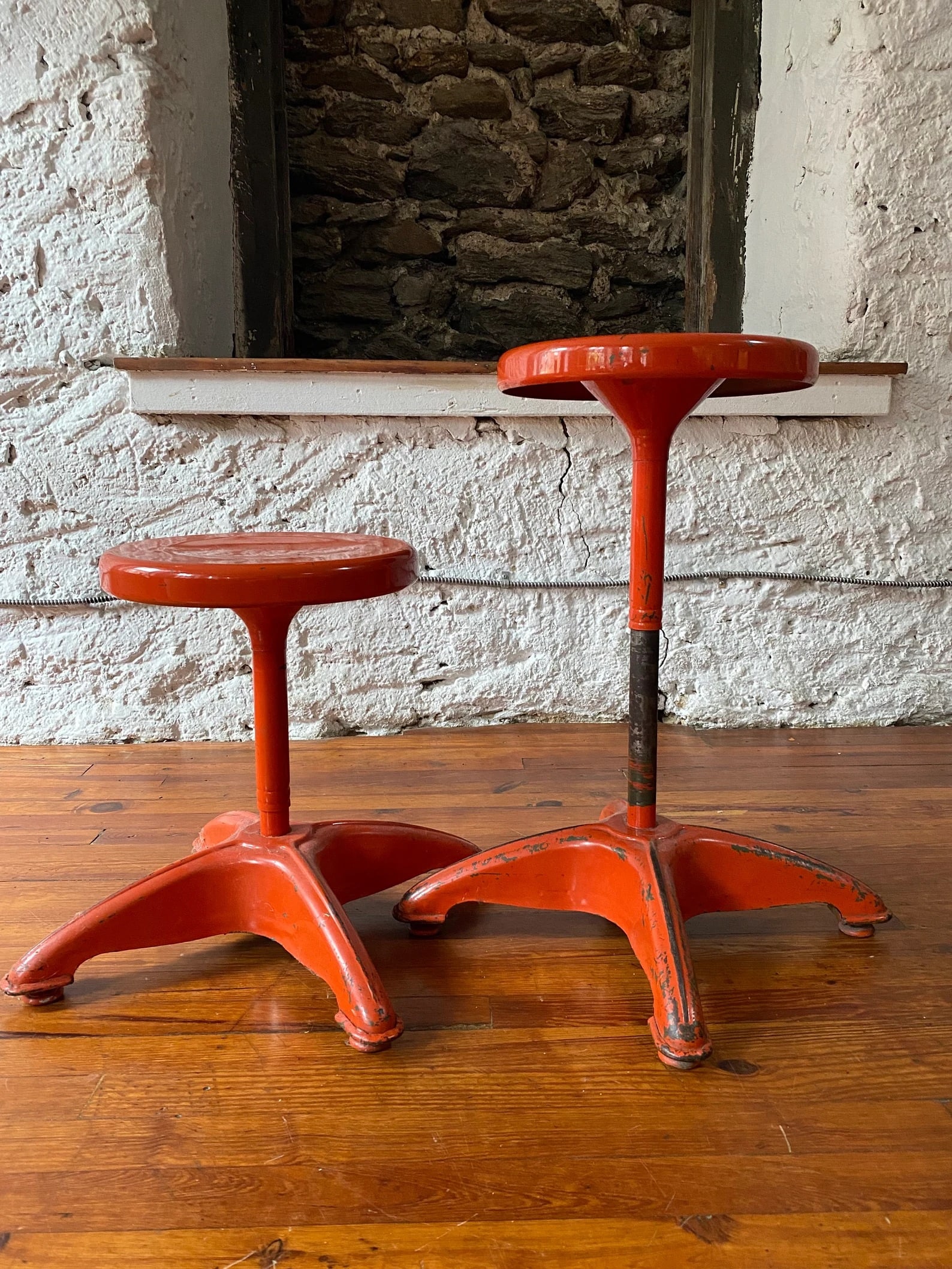 Mid Century Adjustable Bar Stools, Orange Metal Frames, Pair: Pair of mid-century modern adjustable stools featuring orange metal frames with industrial-modern construction. Functional design with height-adjustable mechanism and bold color presence. Ideal for ki