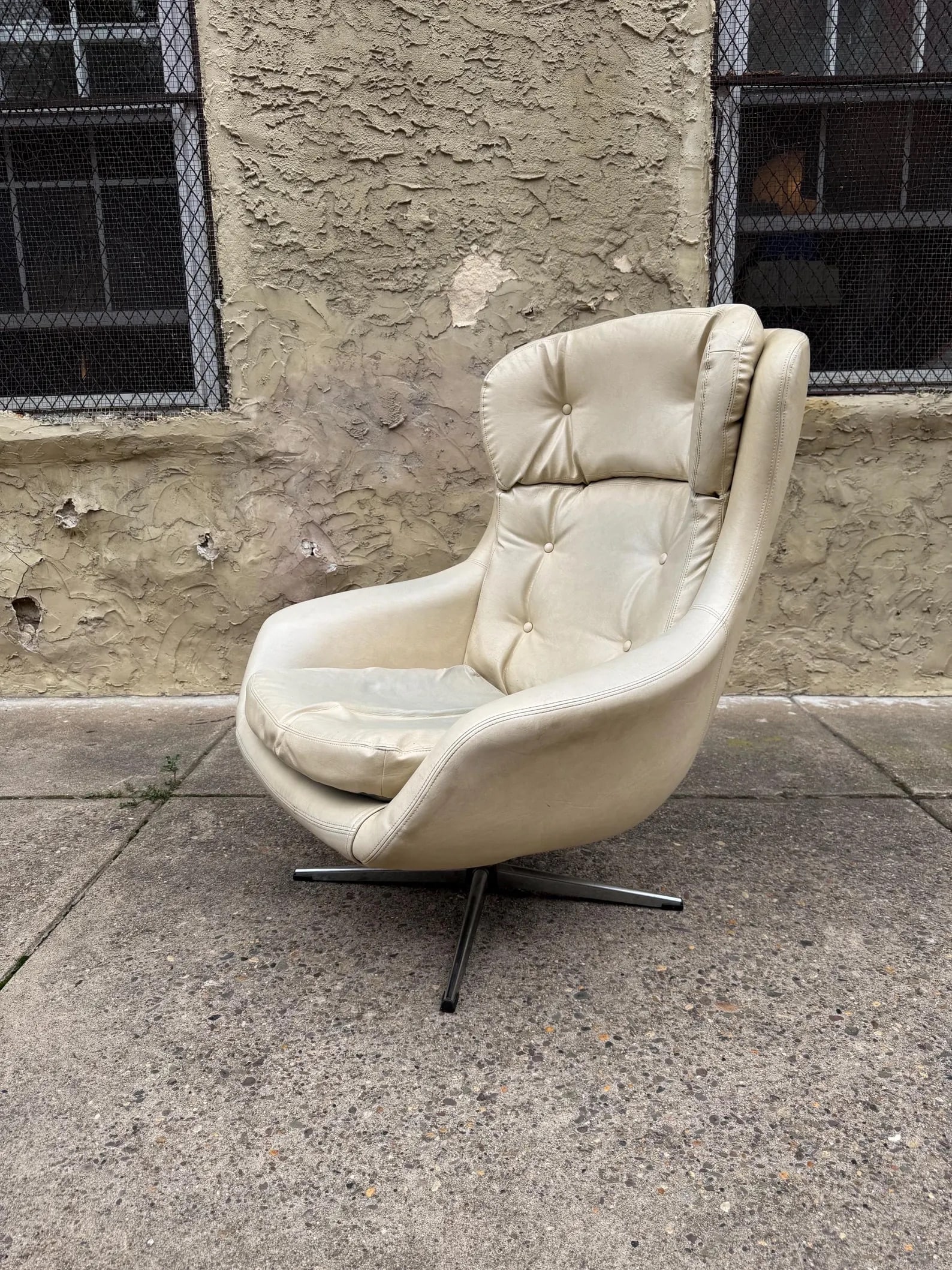 Egg-Style Lounge Chair After Arne Jacobsen: Mid-century modern lounge chair in the manner of Arne Jacobsen’s iconic Egg Chair design. White vinyl upholstery with metal swivel base and reclining back. A dramatic modernist silhouette inspired b