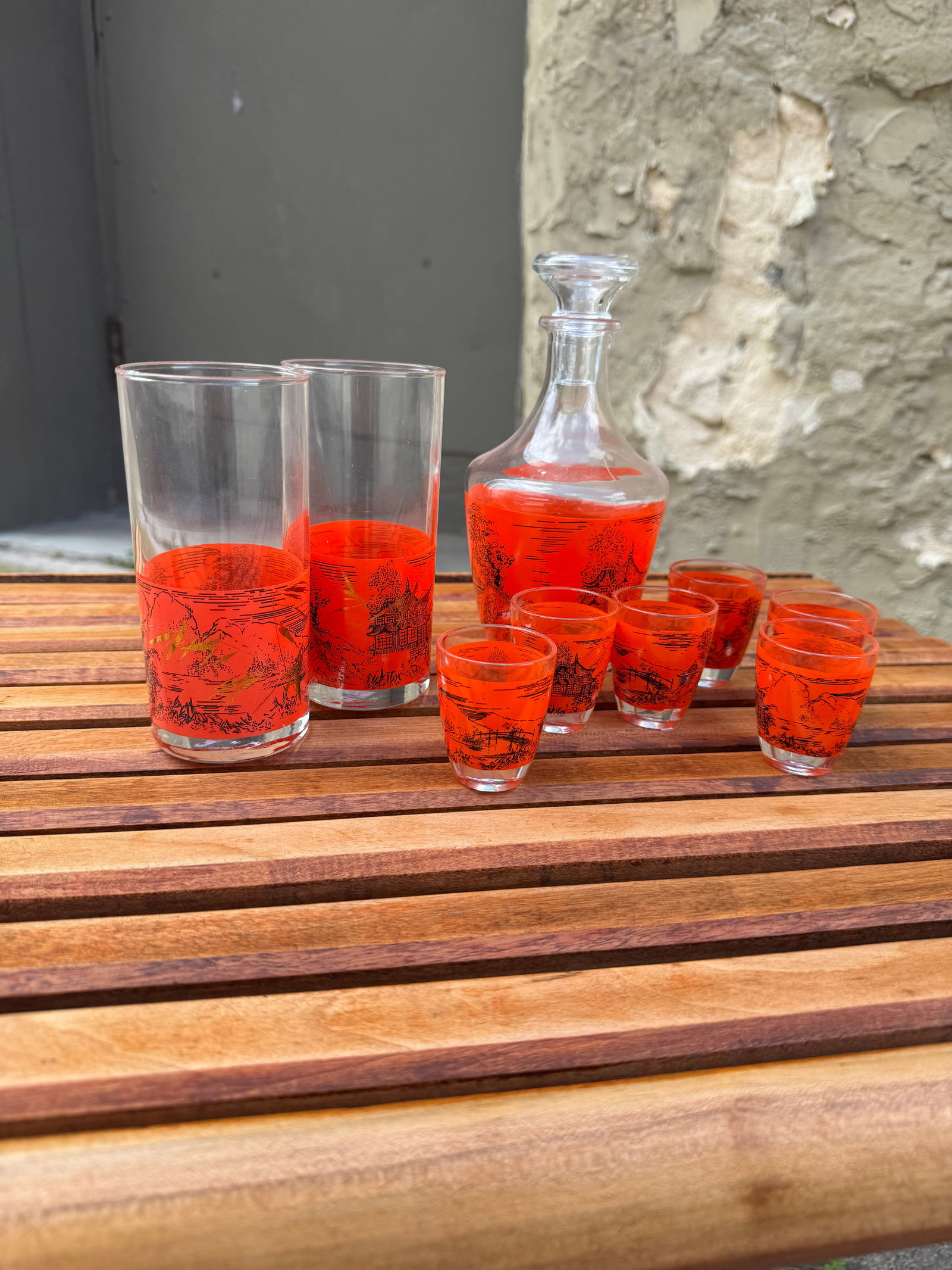Vintage Mid-Century French Orange Pagoda Decanter Set with Glasses: Striking mid-century modern French barware set featuring a vibrant orange enamel band decorated with a black pagoda and landscape motif. Includes a matching glass decanter with stopper, two highball g