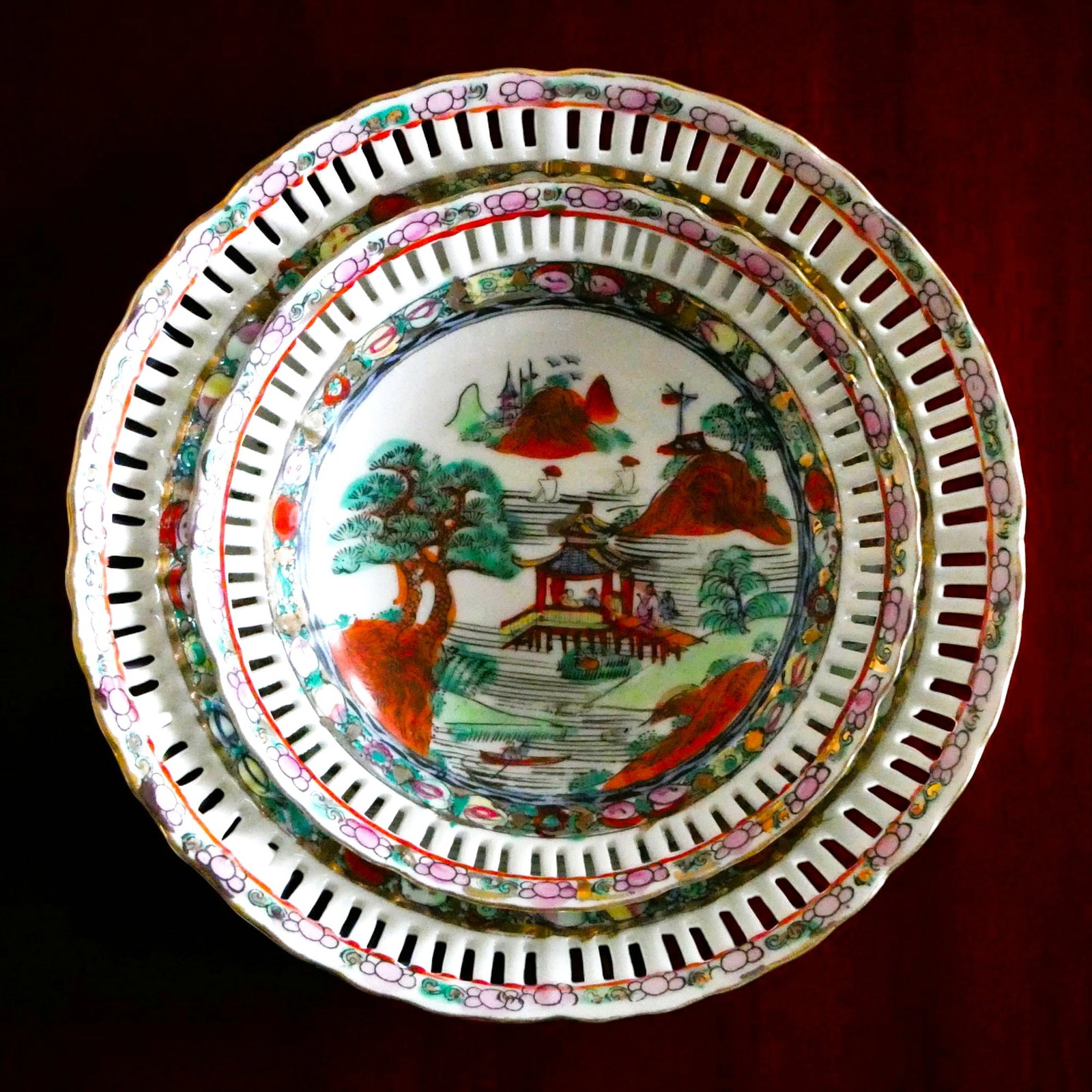 Pair of Chinese Famille Verte Porcelain Reticulated Bowls with Landscape Scenes, 20th Century: This pair of Chinese porcelain bowls, finely reticulated and decorated in overglaze famille verte enamels, measures approximately 18 cm and 23 cm in diameter with respective heights of 6 cm and 7 cm. 