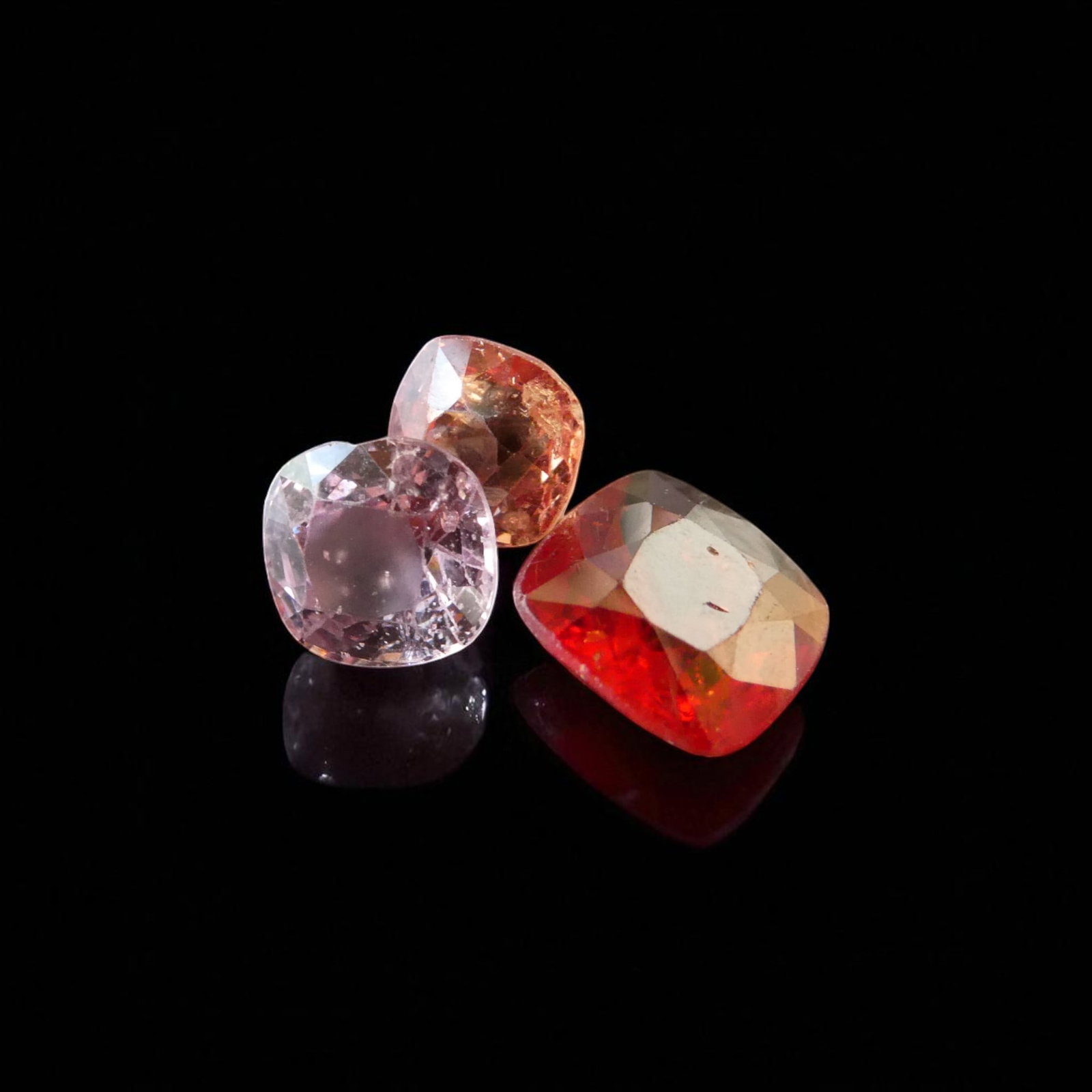 2.8 ct Burmese Spinel 3 pcs Cushion Mixed Colors: A fine trio of natural Burmese spinels with a total combined weight of 2.8 carats, displaying a harmonious blend of warm and cool tones ranging from delicate pink to vivid orange-red. Each stone is ex