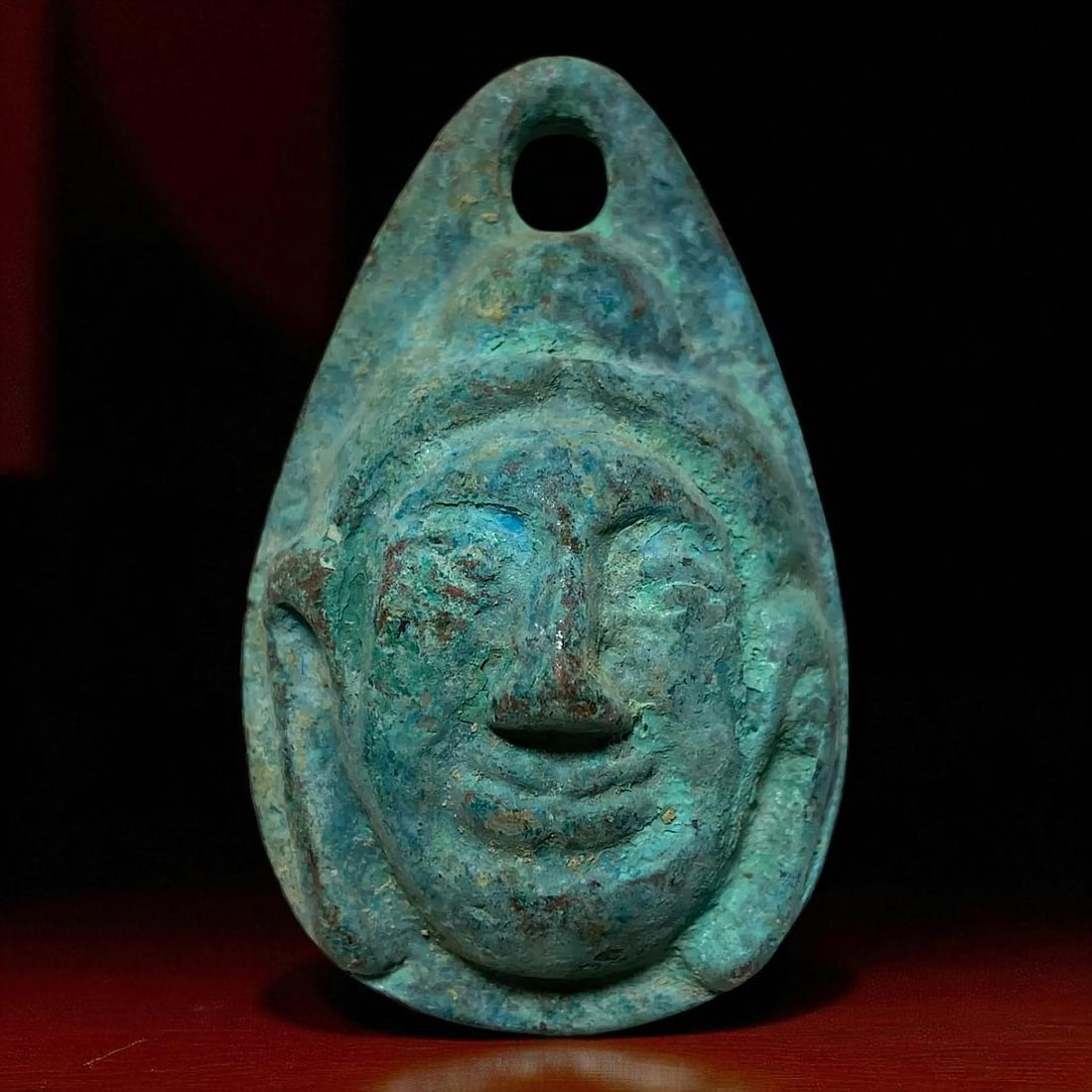 Chinese Bronze Amulet, Buddha/Kwan-yin Face, 53g, Teardrop Form: This striking bronze amulet from China depicts a serene and stylized Buddha or Kwan-yin face, sculpted in high relief on a tear-shaped pendant. Measuring approximately 62 mm in height and 16 mm in thi