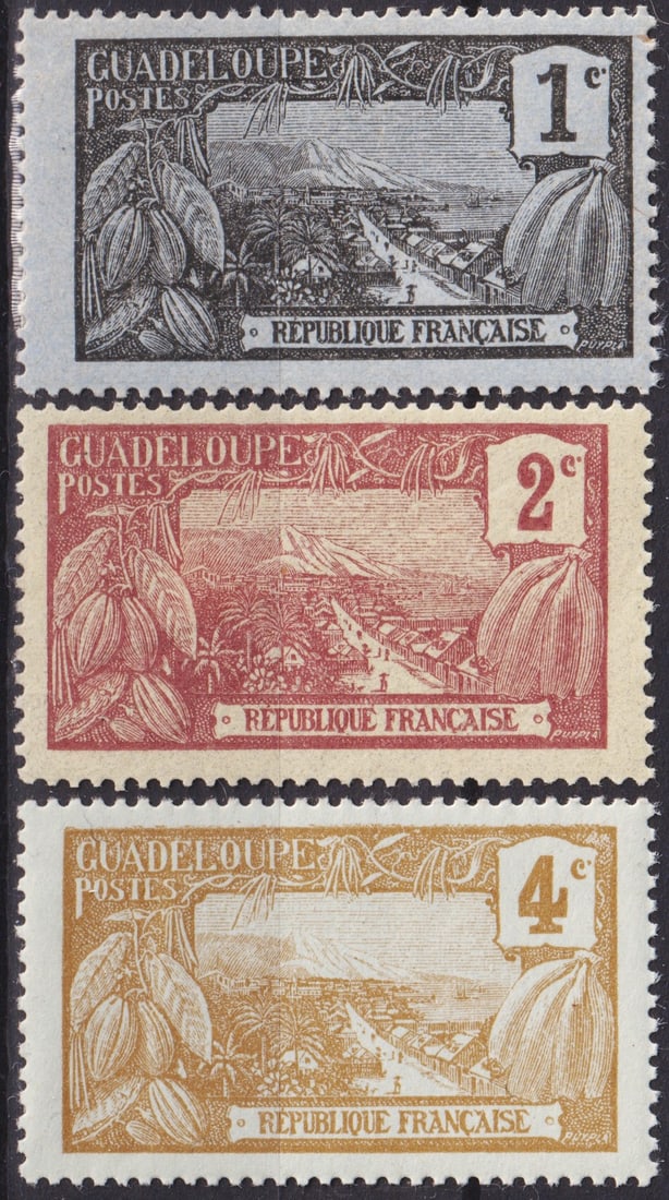 France Guadeloupe 1905–07 Cocoa and Landscape Issue Scott 85–87 MNH Set: A fine set of early colonial issues from Guadeloupe, released between 1905 and 1907, depicting the rich cocoa harvest in the foreground with a panoramic view of the island landscape in the background.