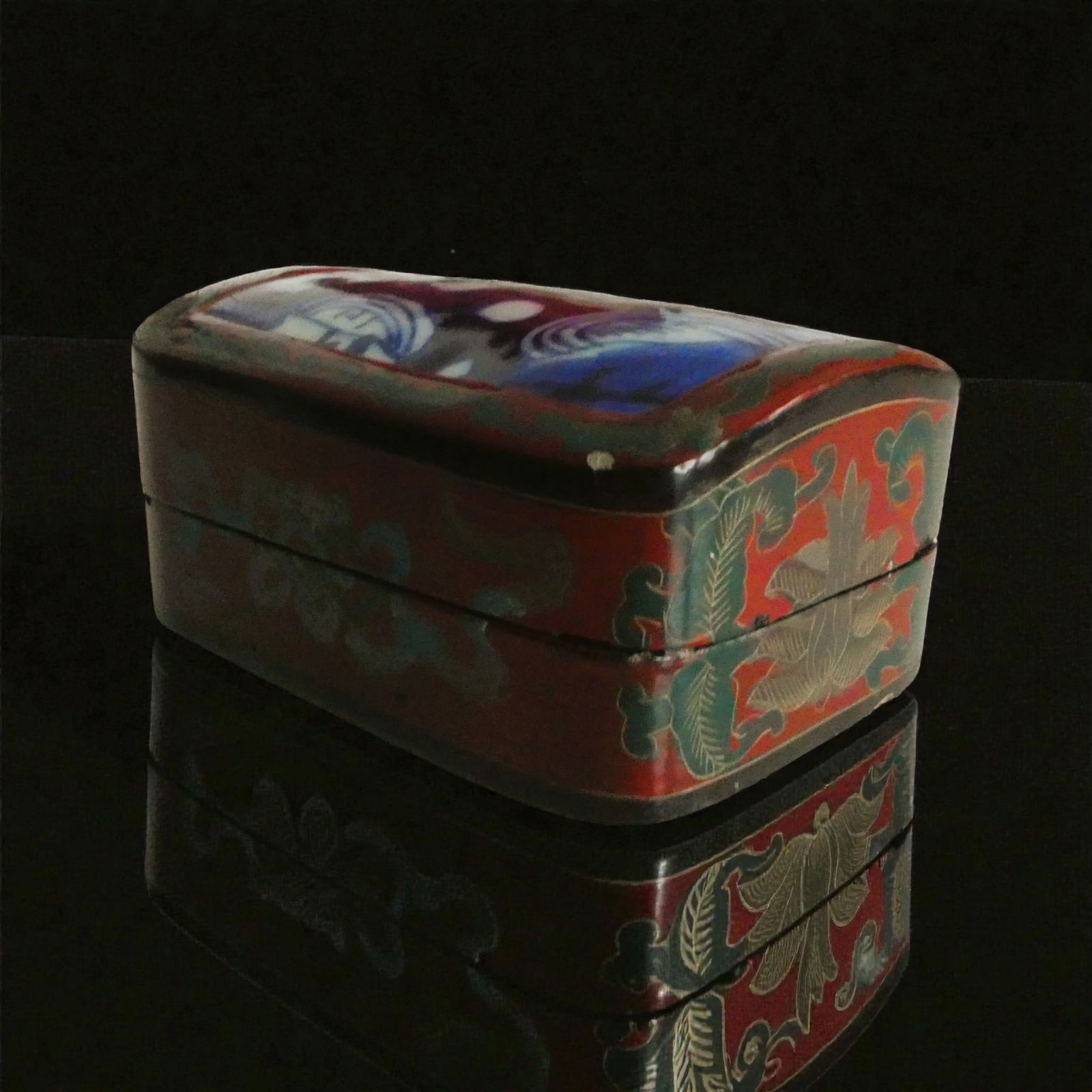 Chinese lacquer wood box with porcelain style lid panel: This decorative Chinese wooden box combines the warmth of hand worked wood with a striking porcelain style panel set into the lid and painted in rich tones of cobalt blue framed by scrolling borders i