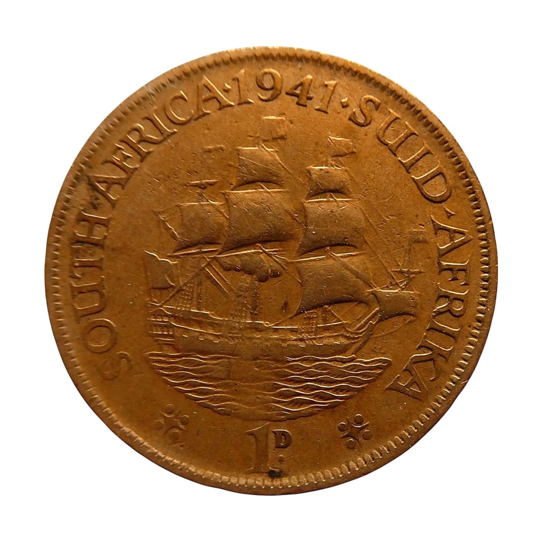 British South Africa 1941 Penny George VI, Sailing Ship Bronze Coin: A fine example of a South African bronze penny issued in 1941 during the reign of King George VI, struck at the Royal Mint in Pretoria. The obverse features the left-facing portrait of King George VI