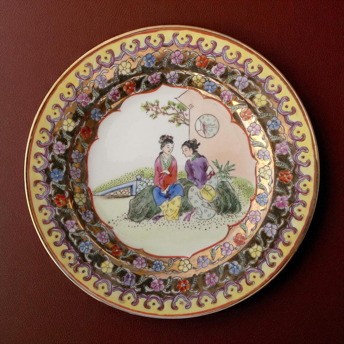 Hand-Painted Famille Rose Export Plate, Macau, "Fabricado em Macau" 1950s: An elegant and finely hand-painted famille rose porcelain plate from mid-20th century Macau, measuring 20 cm in diameter. The central scene depicts two graceful Chinese ladies in conversation within a