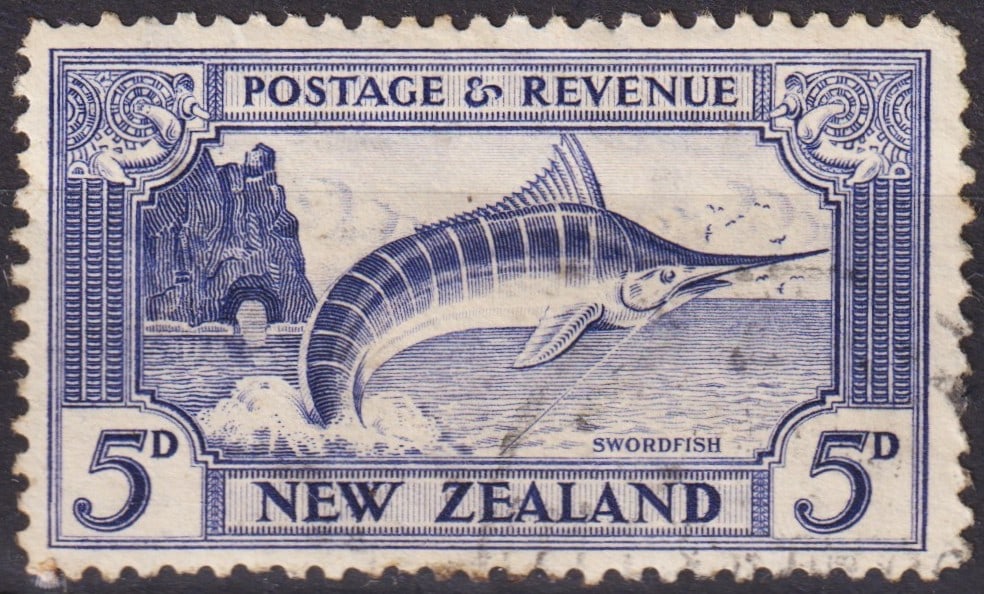 British New Zealand 1935 Swordfish 5d Blue, Scott 192, Second Pictorials: Issued on May 1, 1935, as part of New Zealand’s celebrated Second Pictorial series, this 5 pence ultramarine stamp depicts a dramatic image of a swordfish leaping from the sea, with coastal rock for