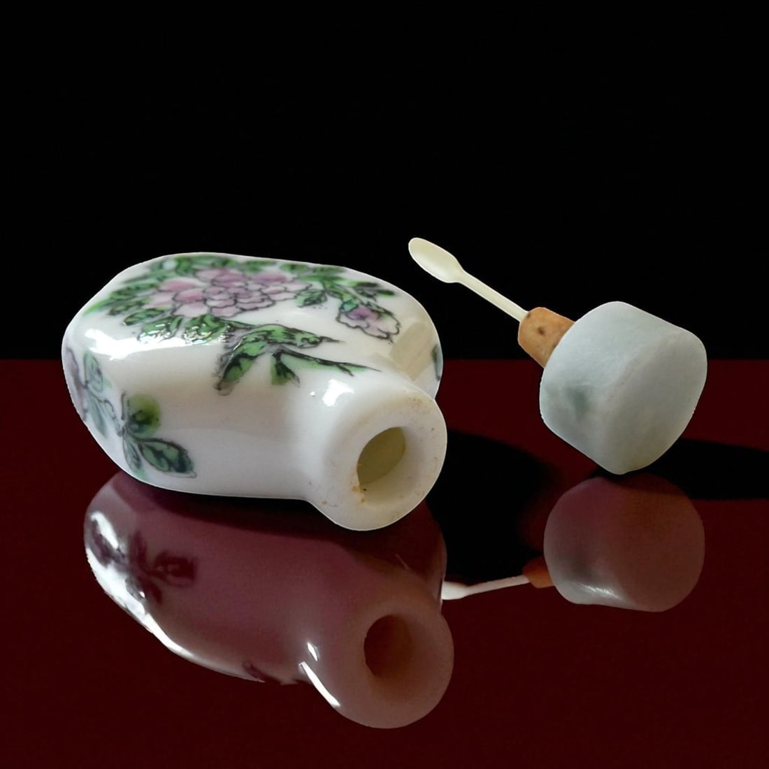 Chinese Famille Rose Porcelain Snuff Bottle, Qianlong Mark, 20th Century: A finely enameled Chinese porcelain snuff bottle, standing 6 cm tall including the stopper (5 cm without), and 3.7 cm at its widest point. The bottle is delicately decorated in the famille rose palett