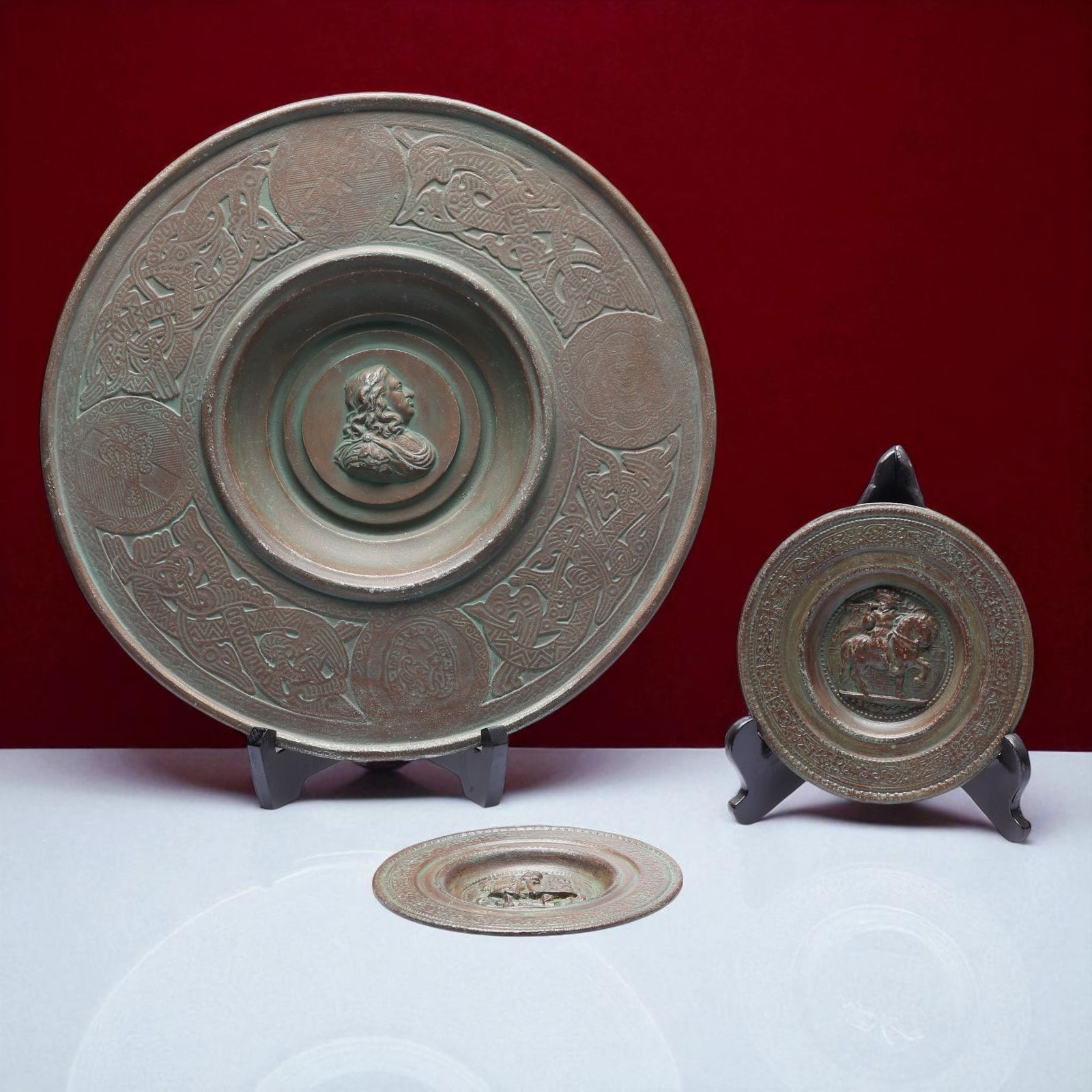 E. USA 18th–19th Century European Bronze Wall Plates with Classical Reliefs: A set of three finely cast patinated bronze wall plaques dating from the 18th to 19th century, attributed to European craftsmanship and marked “E. USA” on the reverse of the largest example, p