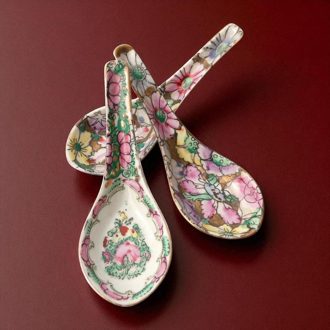Three hand-painted Canton famille rose porcelain spoons, c. 1920s: A charming trio of early 20th century Chinese porcelain spoons, each measuring approximately 14 cm in length, hand-painted in the vibrant famille rose palette. The two spoons feature a densely floral 