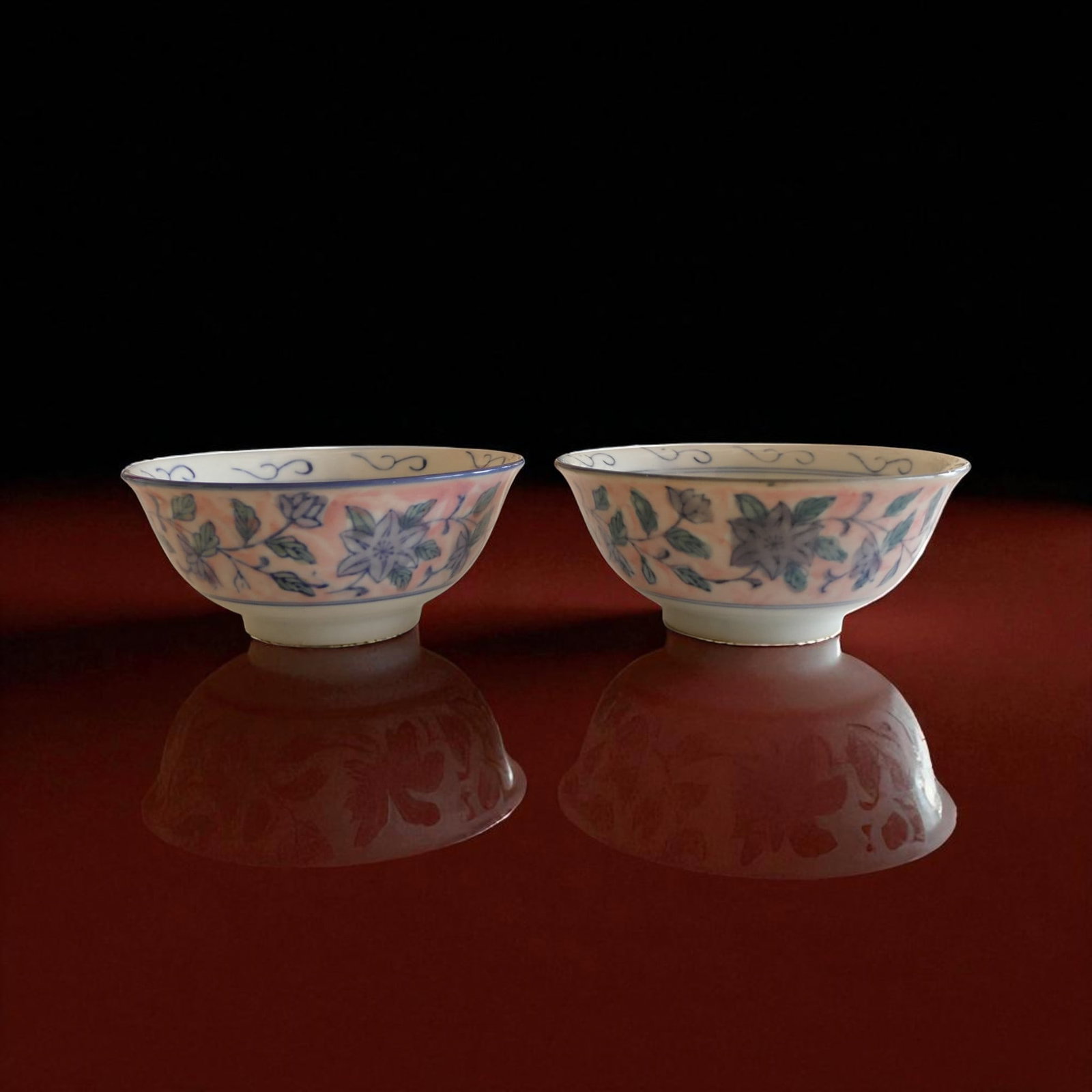Pair of Chinese porcelain bowls with floral decoration, late Qing dynasty: A pair of Chinese porcelain bowls manufactured before 1900, finely decorated in underglaze blue and green with floral motifs enhanced by a delicate pink enamel ground. The exteriors feature a continuo