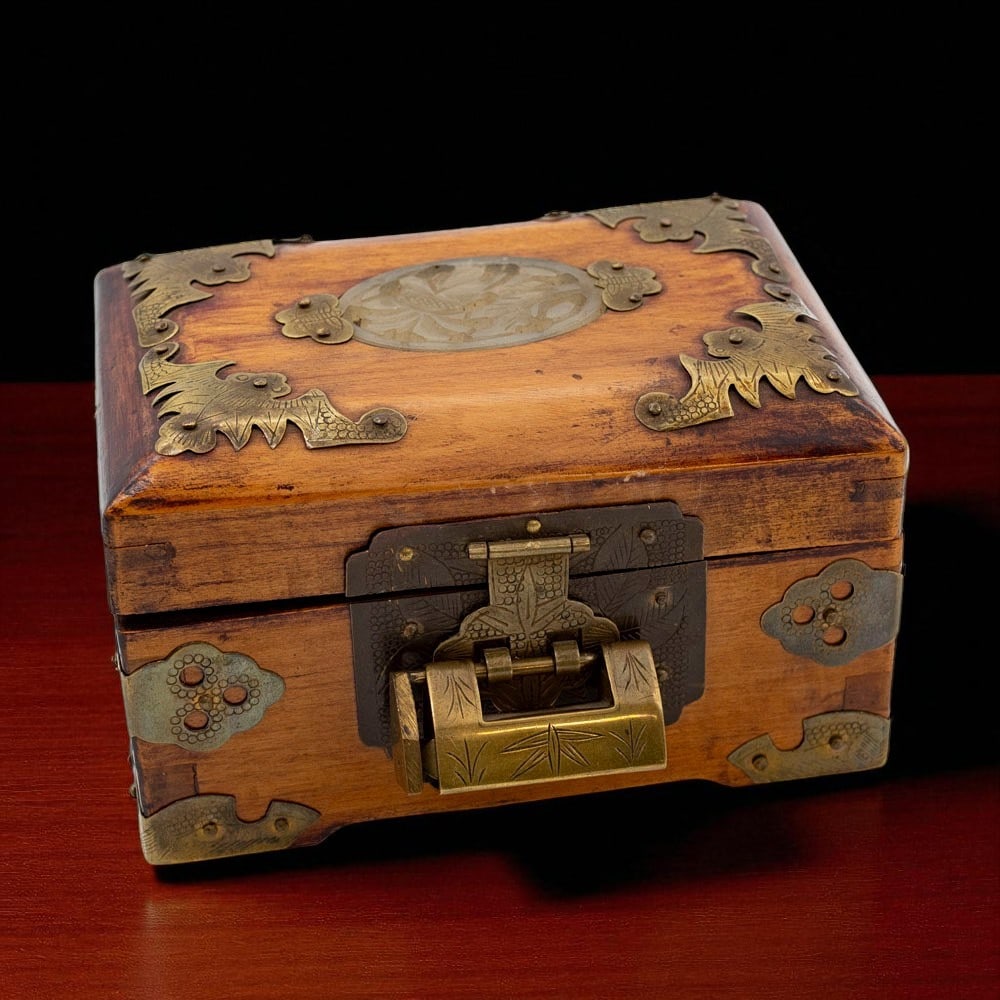 Chinese wooden casket with jade lid and silk interior, Shanghai, ca 1900: A finely crafted Chinese wooden casket from early 20th century Shanghai, decorated with intricate engraved brass fittings in a bat and cloud motif, symbolizing happiness and prosperity. The top of the