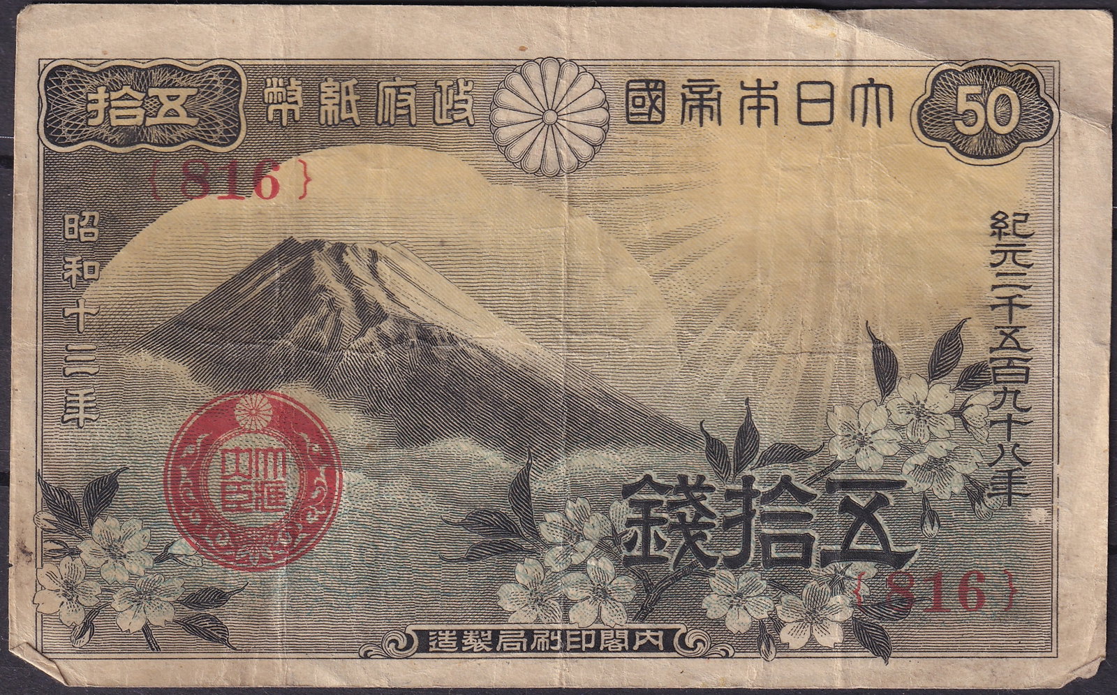 1938 Japan 50 Sen Note with Mount Fuji & Sakura, Showa 13, P-38 (816): This attractive 50 Sen banknote from 1938 (Showa 13) presents an evocative view of Mount Fuji under radiant sunrays, bordered with cherry blossoms in full bloom — an image that united spiritual reve