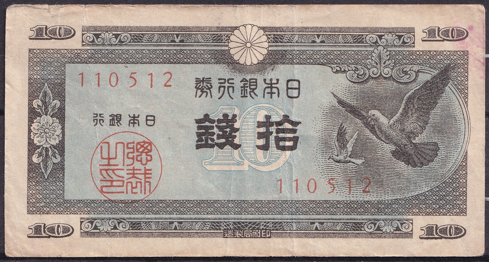 1946 Japan 10 Sen Banknote with Doves and Parliament Building: Beskrivning: Issued in 1946 by the Bank of Japan, this 10 sen banknote is a poignant artifact from the early postwar reconstruction period, symbolizing peace and national recovery. Printed in multicol
