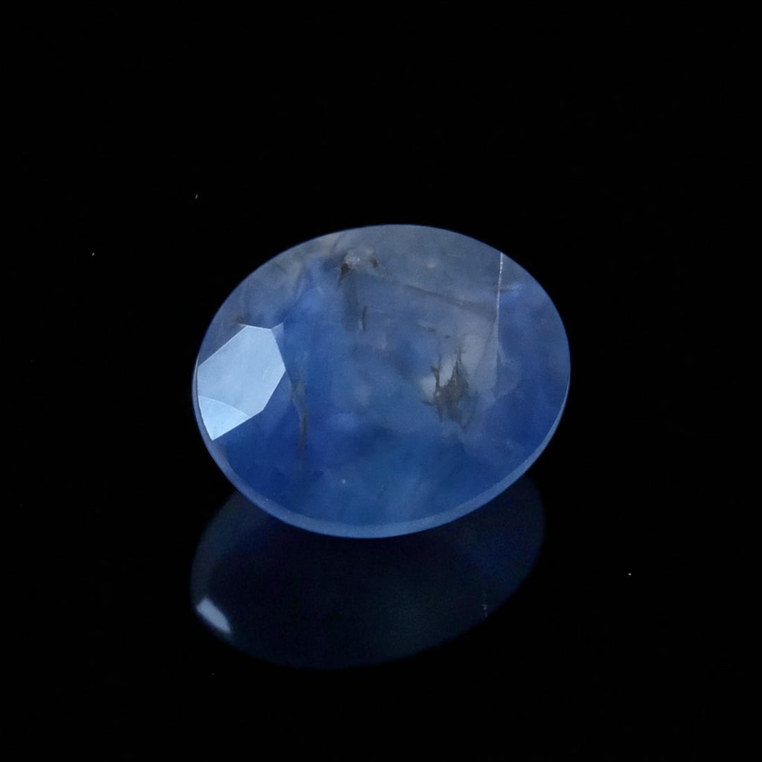 Certified Natural Sapphire, 0.80 ct Oval Mixed Cut, ALGT: A natural blue sapphire weighing 0.80 carat, cut in an oval mixed style and measuring 5.44 x 4.73 x 3.27 mm, this gemstone showcases a uniquely uneven blue hue with internal inclusions visible to the 