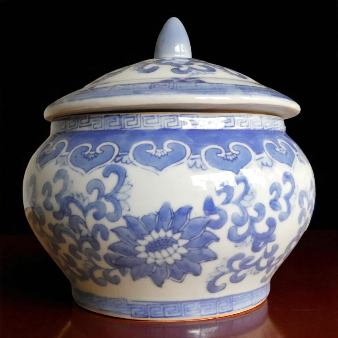 Qing Dynasty Blue and White Covered Jar, 19th Century, China: This impressive lidded porcelain jar originates from China and is finely decorated in underglaze cobalt blue with bold floral scrolls and lotus blossoms, framed by a classic Greek key border around th