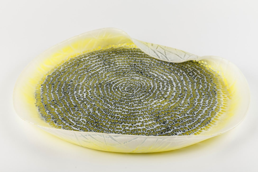Amanda Simmons 'Northlands Platter': Amanda Simmons doesn't simply shape glass in the kiln -- she collaborates with gravity. In Northlands Platter, hundreds of tiny marks spiral outward from the center in rings of yellow, gray, black,