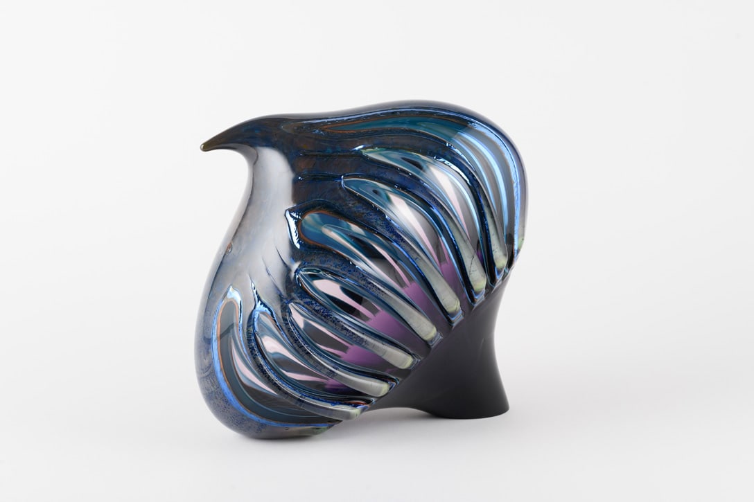 Richard Royal 'Love Bird from the Diamond Cut Series': Richard Royal's Love Bird appears caught in motion. Dark glass sweeps forward into a beak-like point while a series of dramatic cuts opens the surface to reveal layers of pale blue, white, pink, and