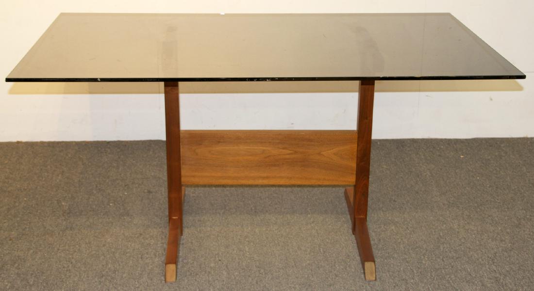 Modern Design Dining Room Table: A modern design dining room table with a walnut trestle base and smoked glass top. 29 in tall x 60 in wide x 36 in deep. Provenance: From the estate of Ray Neye, Brookhaven PA.