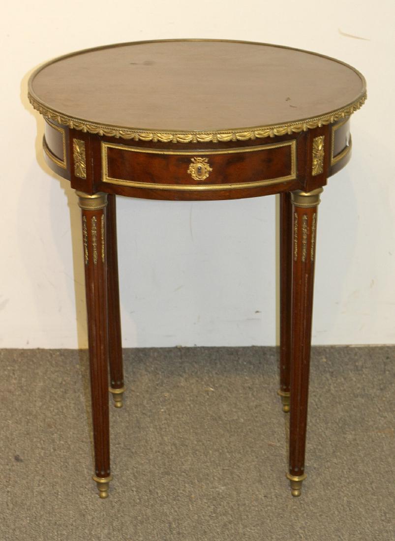 Louis XVI-style Mahogany Gueridon: A Louis XVI-style mahogany gueridon with gilt metal mounts, single drawer, and reeded legs. 29H x 23 DIA in.