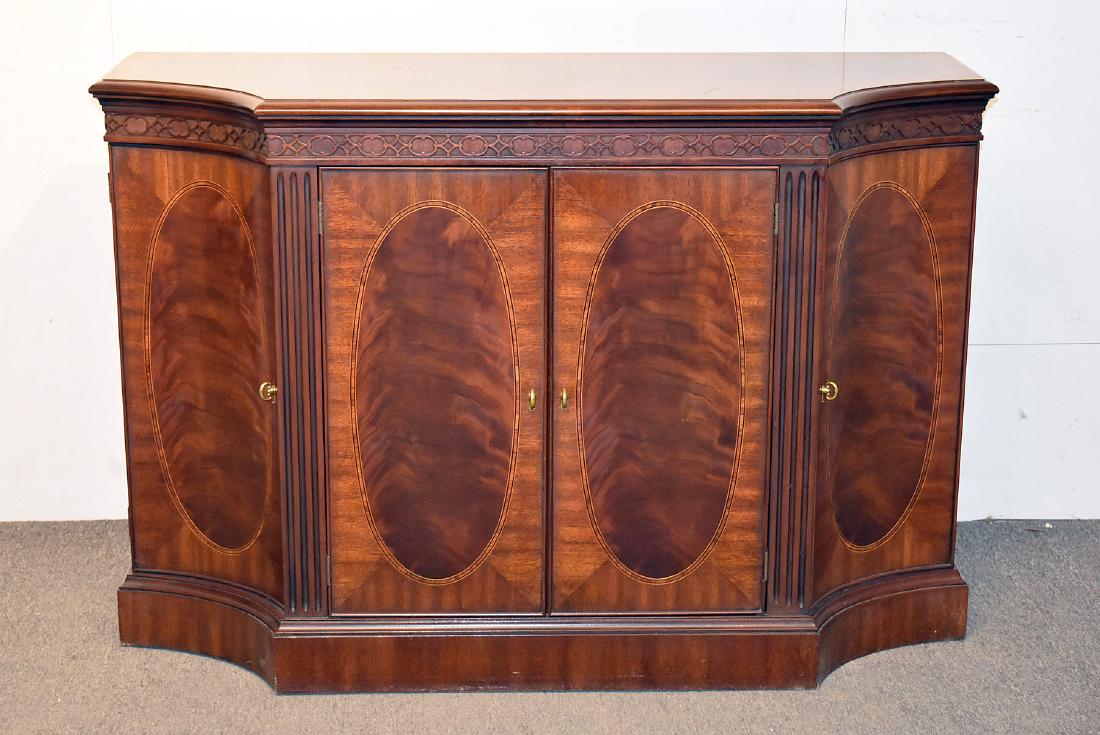 Henkel Harris Mahogany Credenza: A Henkel Harris model 2351 mahogany credenza with a banded top over a case with gothic carved frieze, conforming doors with figured mahogany ovals and banding, and fluted pilasters. 34 in tall x 51 in