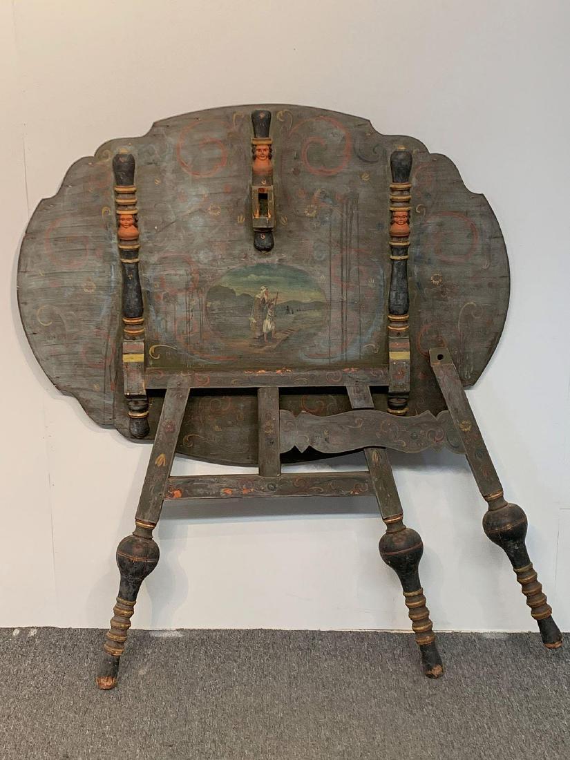 Portuguese Colonial-style Painted Wine Table: A 19th C. Portuguese Colonial-style wine tasting or tea table with a tilting floral painted top, the underside mask carved with figural/landscape decoration, on turned legs. 31in tall x 43in wide x 32