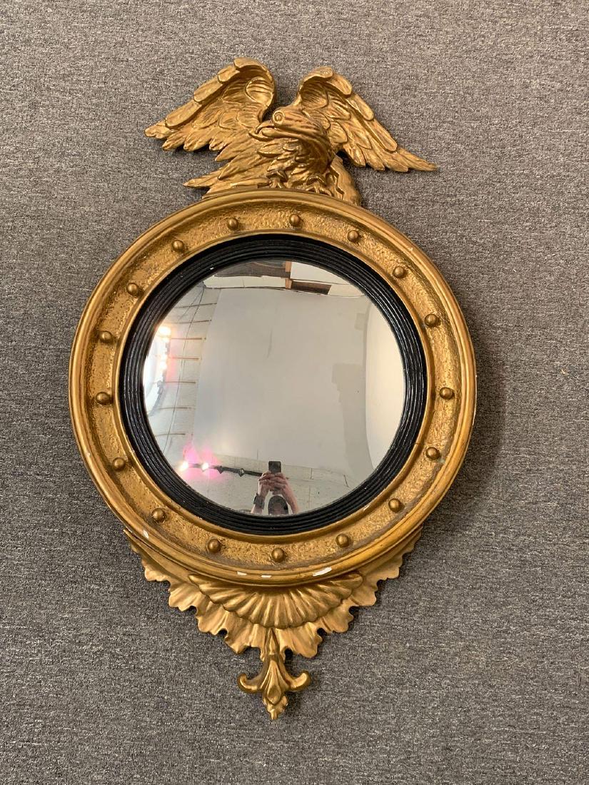 Regency-style Eagle Convex Mirror: A Regency-style giltwood convex mirror crested with an eagle, with leaf-form pendant below. 42in tall x 26in wide.