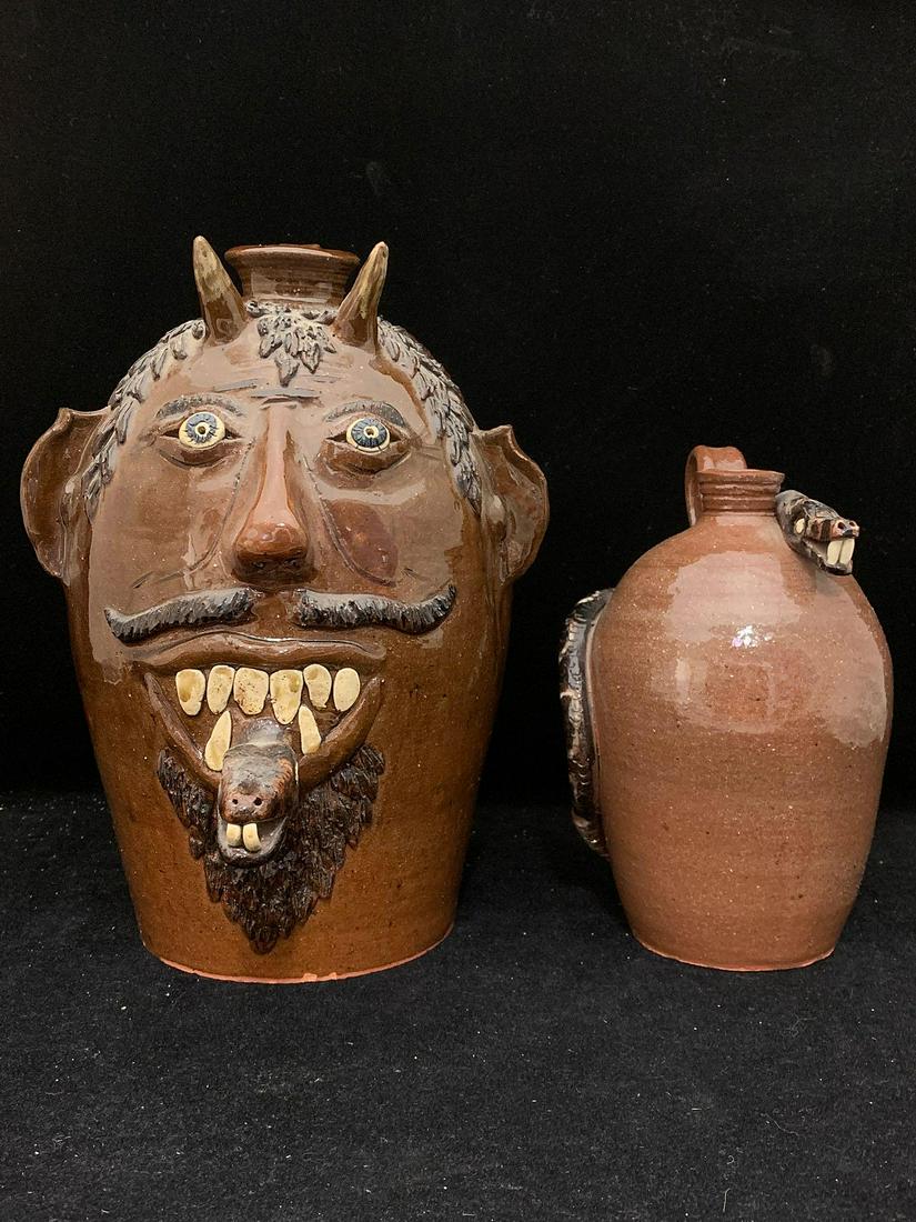 Two Albert Hodge Pottery Jugs: Two Albert Hodge folk art jugs to include a devil face jug and a snake jug. Both are signed. Larger: 12 in tall x 9 in x 8 in.