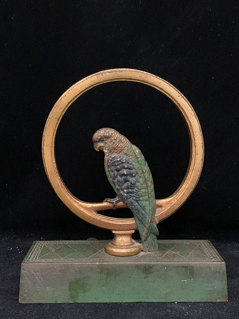 Cast Iron Parrot in Ring Doorstop: A cast iron parrot in ring doorstop, likely Bradley and Hubbard, with double sided parrot perched inside a ring. 8 in tall x 7 in wide x 3-1/4 in deep.