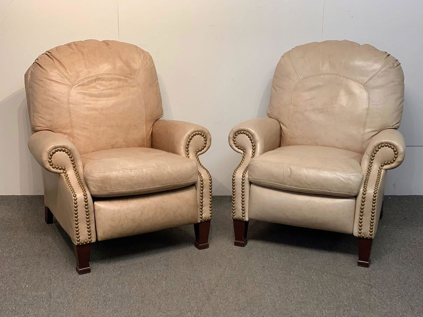 Pair of Bradington Young Leather Recliners: A pair of labeled Bradington Young leather recliner lounge chairs with brass tacked trim and mahogany legs. 38in tall x 35in wide x 32in deep.