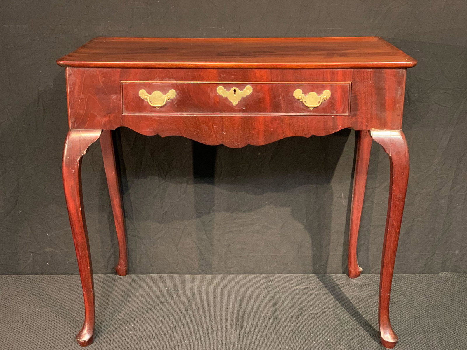 Queen Anne Mahogany Tea Table: An 18th C. mahogany Queen Anne tea table with shaped rectangular top with raised lip, over an apron with central drawer and slide out trays, raised on cabriole legs. 28-1/4in tall x 31-1/2in wide x 18