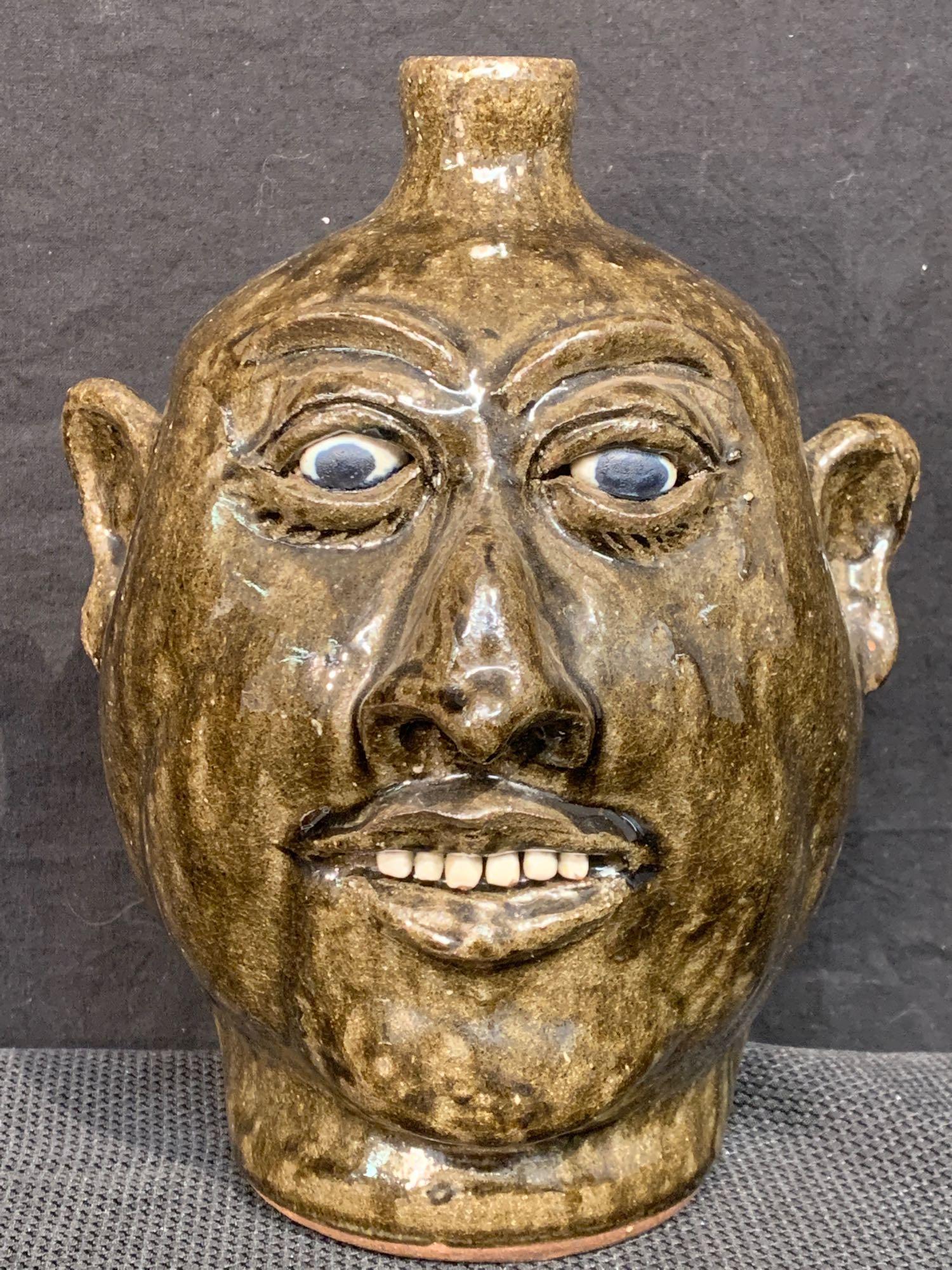 Lanier Meaders Glazed Pottery Grotesque Face Jug: Lanier Meaders (Georgia, 20th C.). A folk art glazed pottery grotesque face jug. Signed on base. 10in tall.