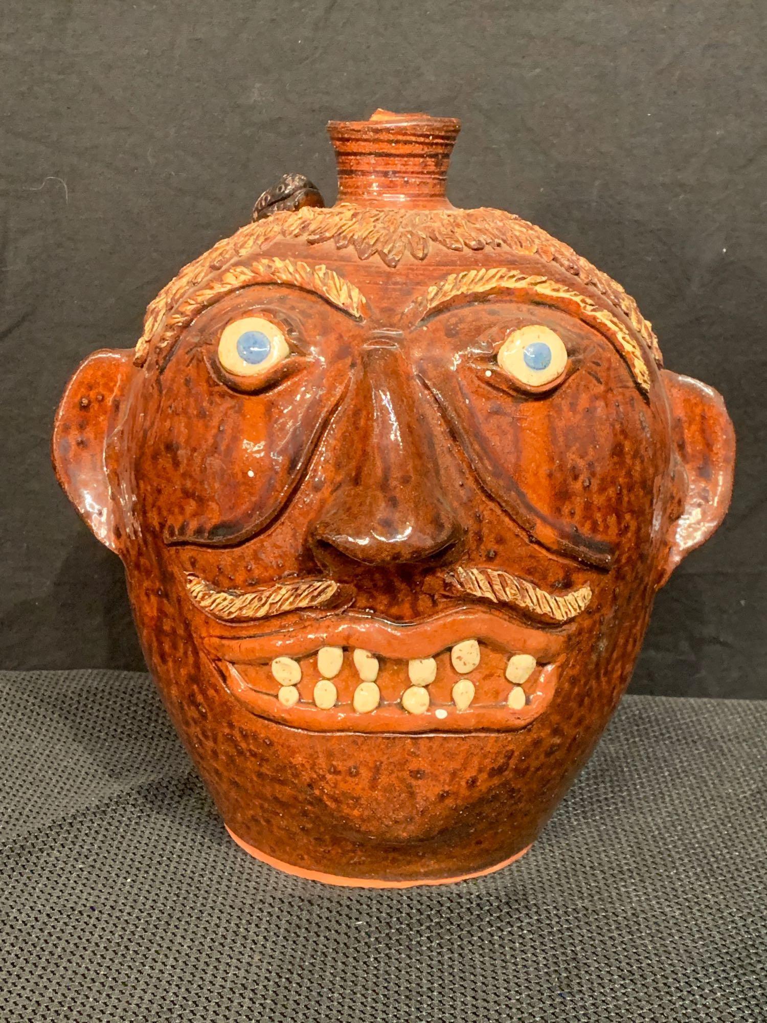 Albert Hodge Glazed Pottery Grotesque Face Jug: Albert Hodge (North Carolina, 20th C.). A folk art glazed pottery grotesque face jug with lizard. Signed on base. 11in tall.