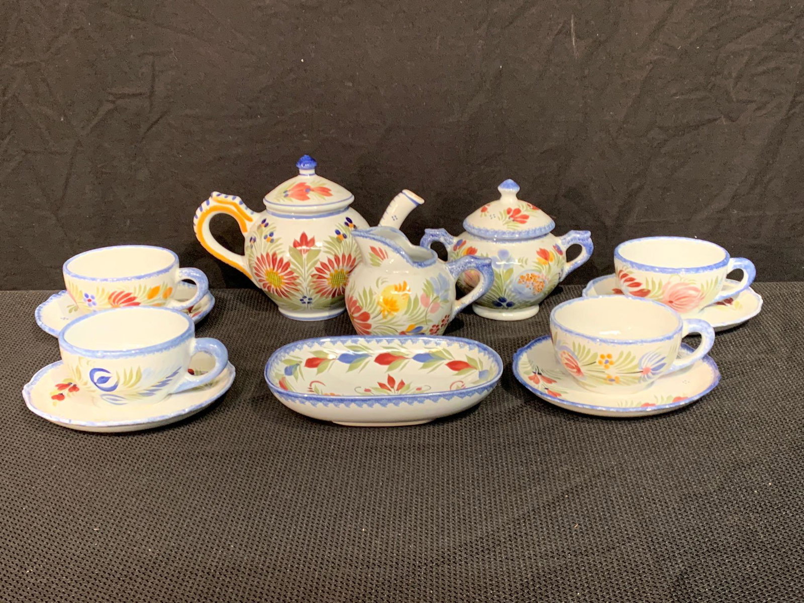 Twelve-pc. Henriot Quimper Pottery Tea Set: A twelve-piece Henriot Quimper French pottery tea set comprised of a teapot, lidded sugar, cream pitcher, small dish, and four cups with saucers. All marked. Teapot: 6in tall x 8-1/2in wide.
