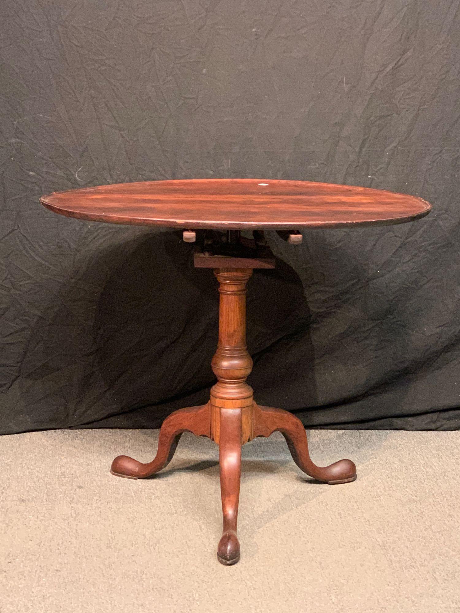 18th C. Queen Anne Tea Table: An 18th C. Queen Anne tilt-top tea table with dish top, suppressed ball standard shaft, and cabriole legs. 28-1/2in tall. Top: 33-1/4 x 34-1/2in.