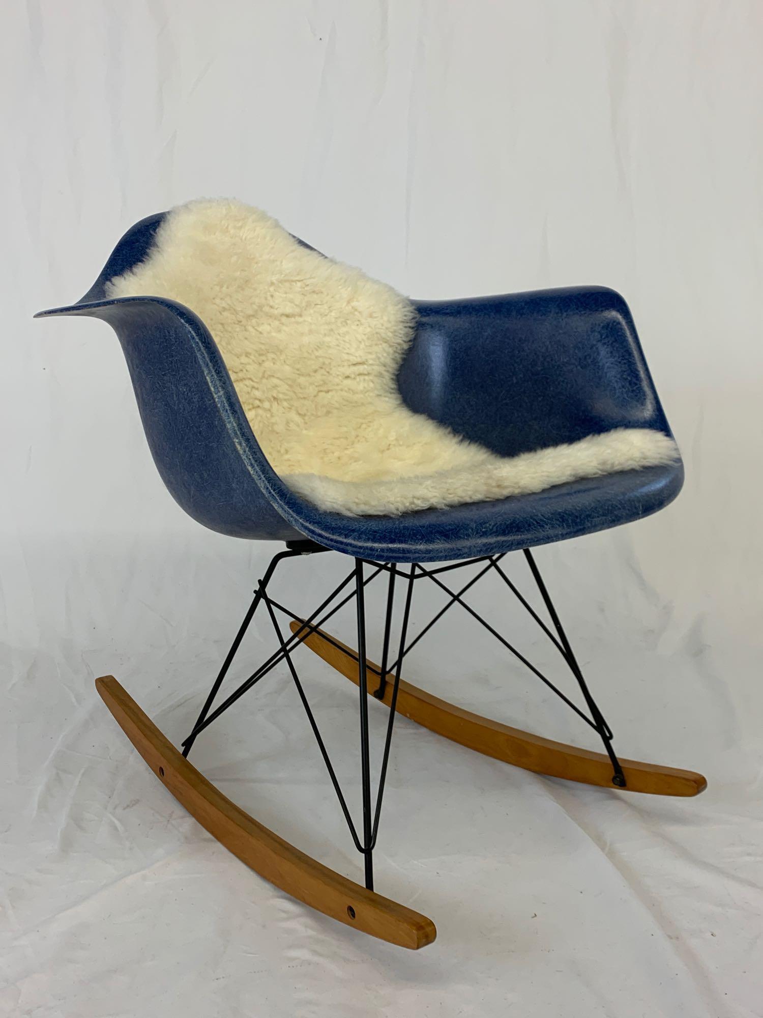 Eames/Herman Miller RAR Rocking Chair: A Charles & Ray Eames for Herman Miller RAR rocking chair with blue shell, black steel frame, wooden runners, and with later sheepskin attached via Velcro. Paper label and raised stamp. Dated January