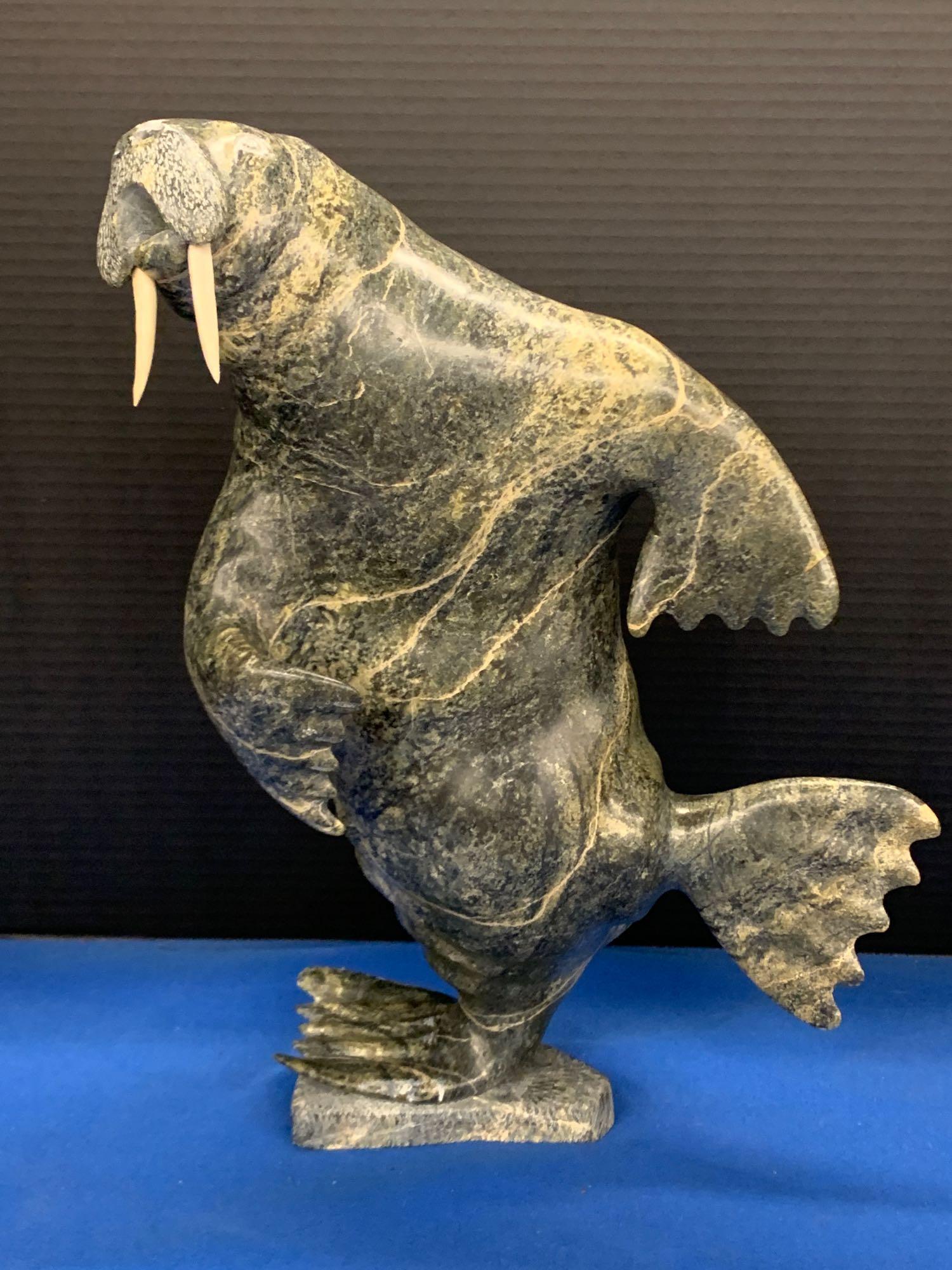 Inuit Carved Soapstone Sculpture, Walrus: An Inuit carved soapstone sculpture of a standing walrus by Lucassre Ikkiduak (B. 1949). Marked on base. 14in tall.