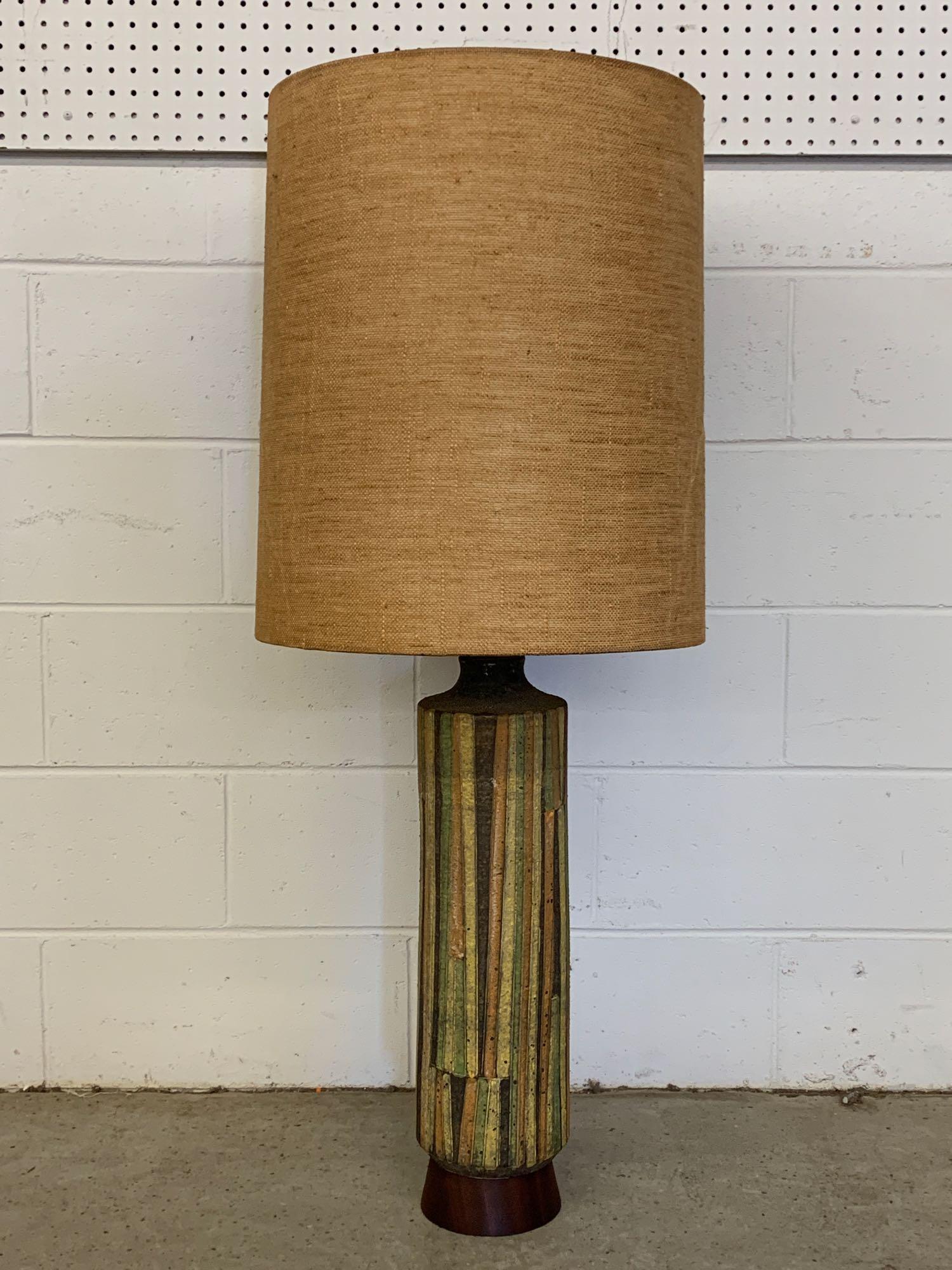 Large Italian Raymor Pottery Table Lamp: A large Italian pottery table lamp by Raymor, circa 1950s, with knife-cut ceramic vase base in green, yellow, orange, and brown. Walnut base and top with drum shade. Signed on base. Base: 26in tall. H