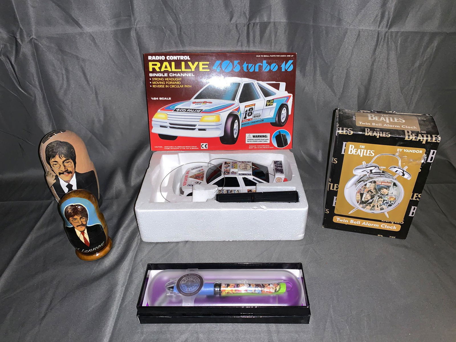 Grouping of Beatles Memorabilia: A grouping of Beatles memorabilia including a twin bell alarm clock, two nesting dolls, a "Sergeant Peppers" pod pen and a remote control Rallye 405 turbo 16.